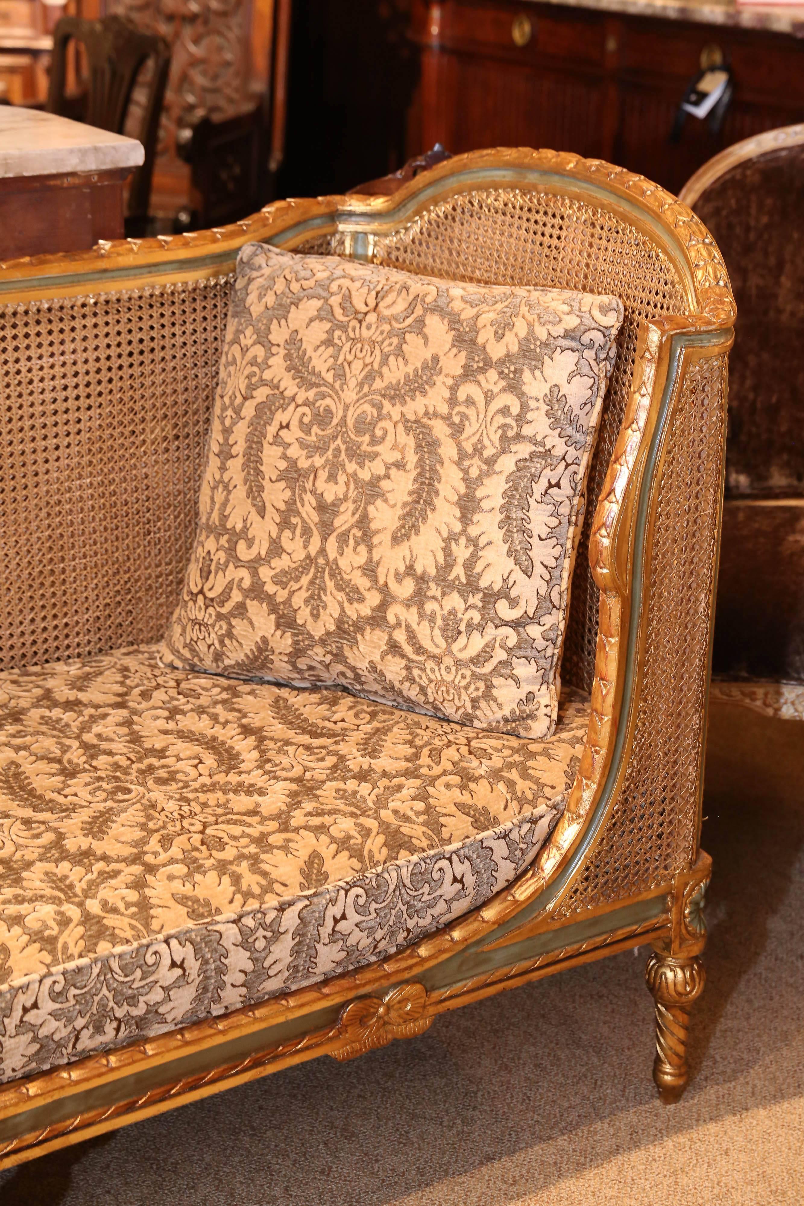 High back settee with a carved giltwood frame with a laurel leaf design and
concave ends. The crest rail rises to. Curved ends of concave painted
molding with vertical painted supports that create the frames on which
the cane is stretched inside