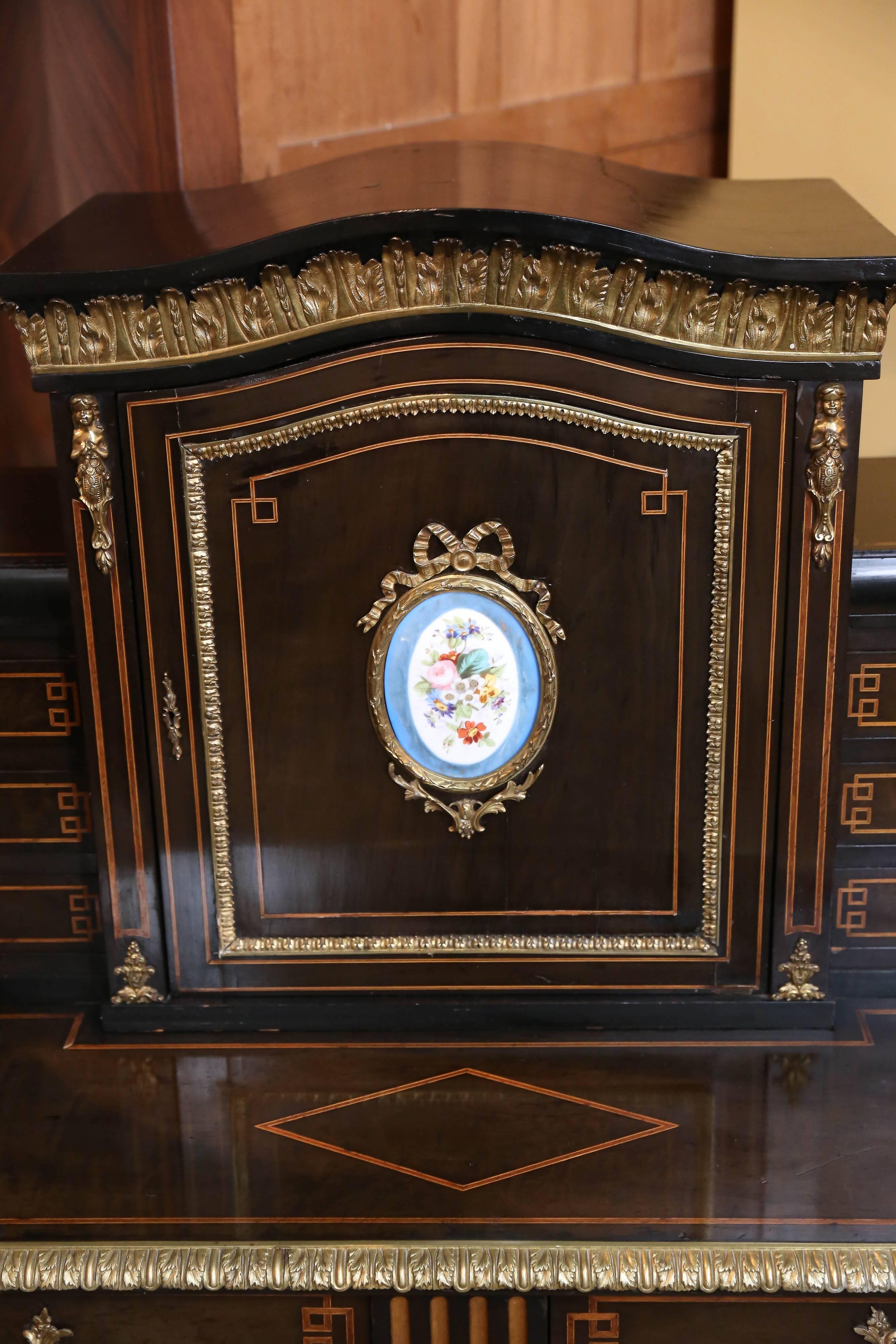 French Louis XVI style desk having floral porcelain Sèvres mounts
The upper portion of this desk has a door that opens to a rosewood interior
with one shelf bronze mounts decorate the edge of this fine piece.
Three drawers are on each side of