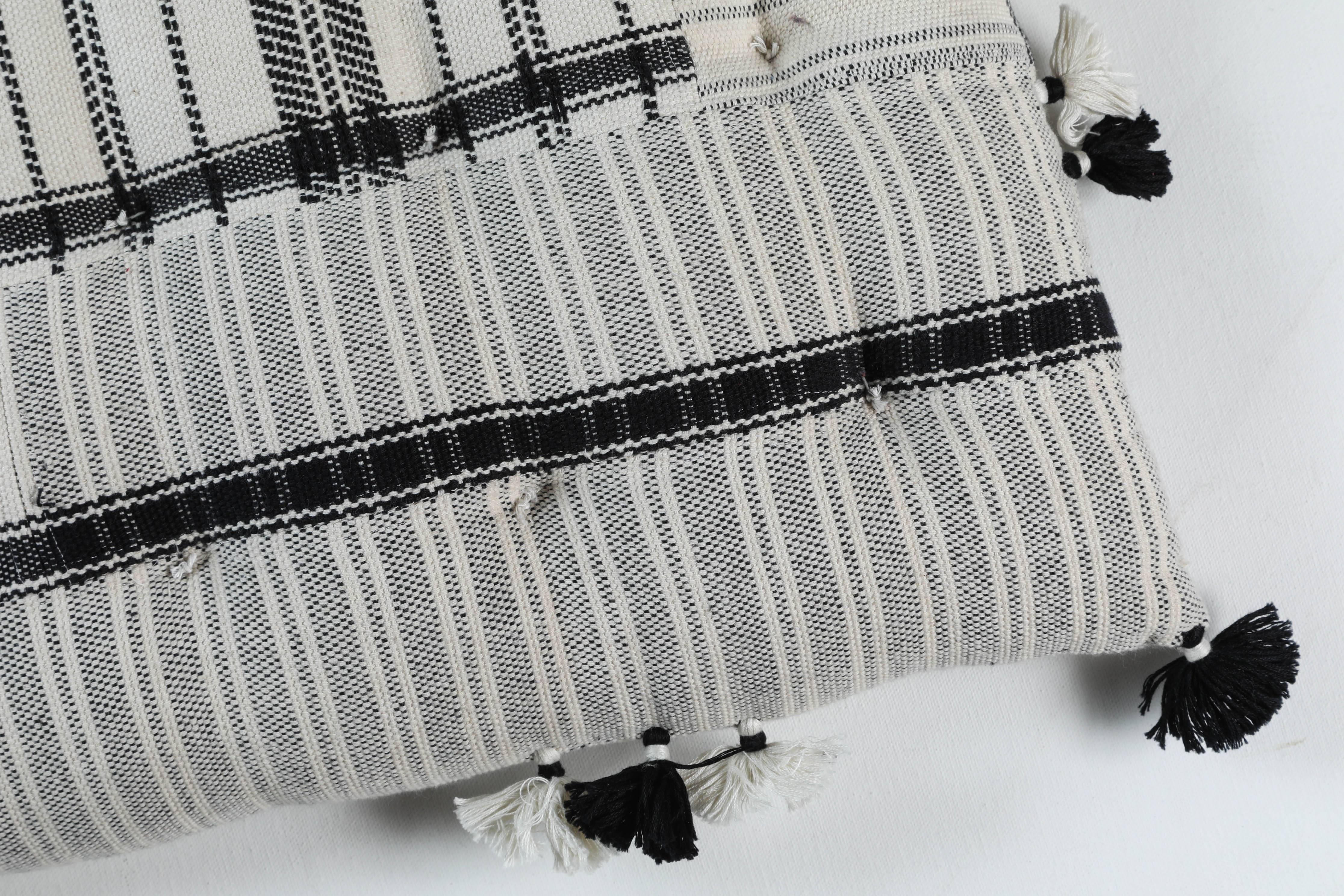 Kala naturally dyed organic cotton from Gujarat, India. Hand loomed using traditional Indian textile techniques to produce extra weft woven stripes and plaids. This black and white striped pillow has added hand-knotted tassels.