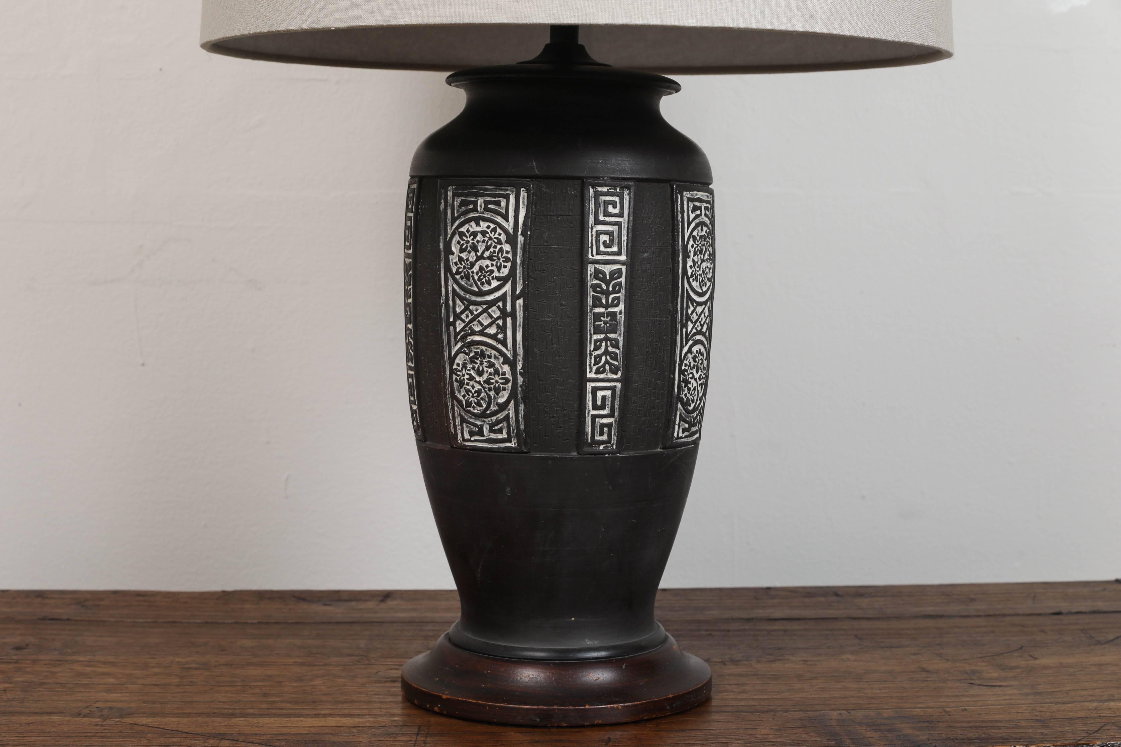Vintage Chinese black ceramic. Inset designs detailed with white. Stands on a wood base. Updated hardware and twist cord wiring. Custom taupe linen shade with diffuser.