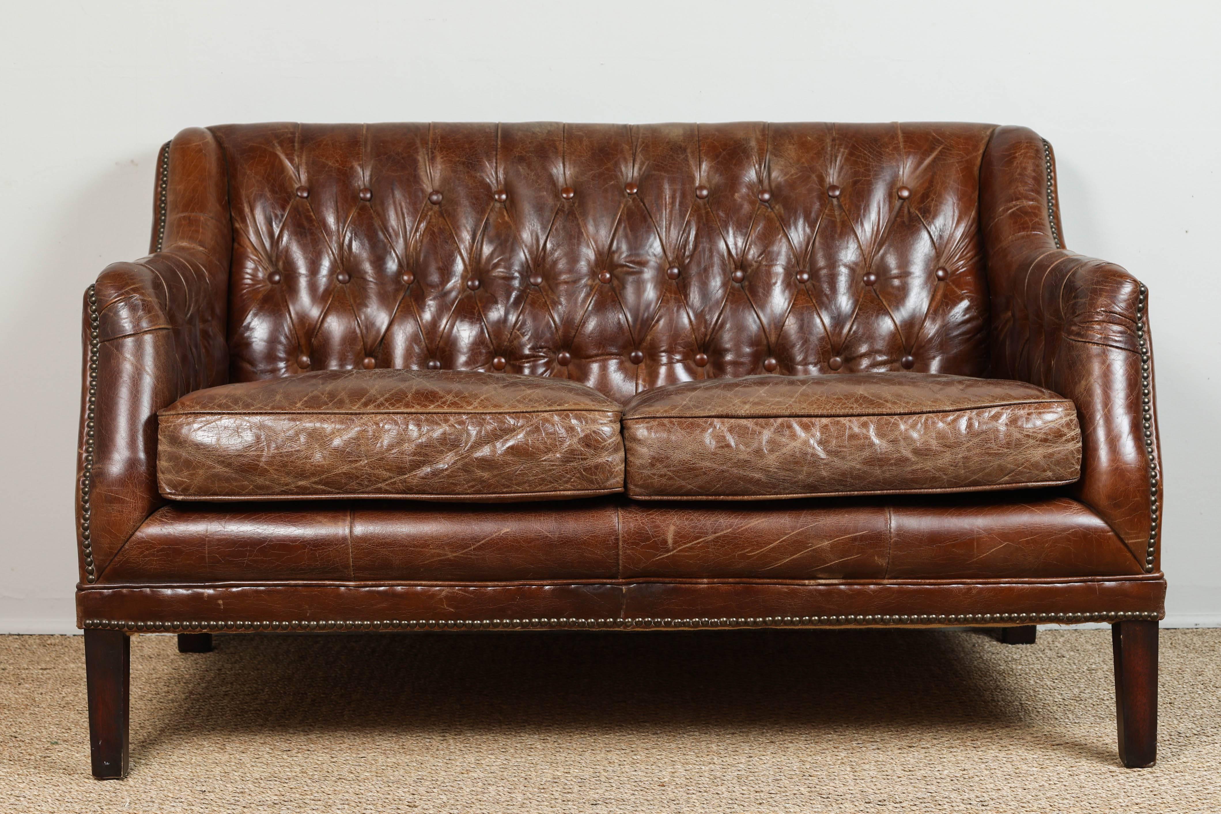 Aged to perfection distressed tufted leather loveseat.