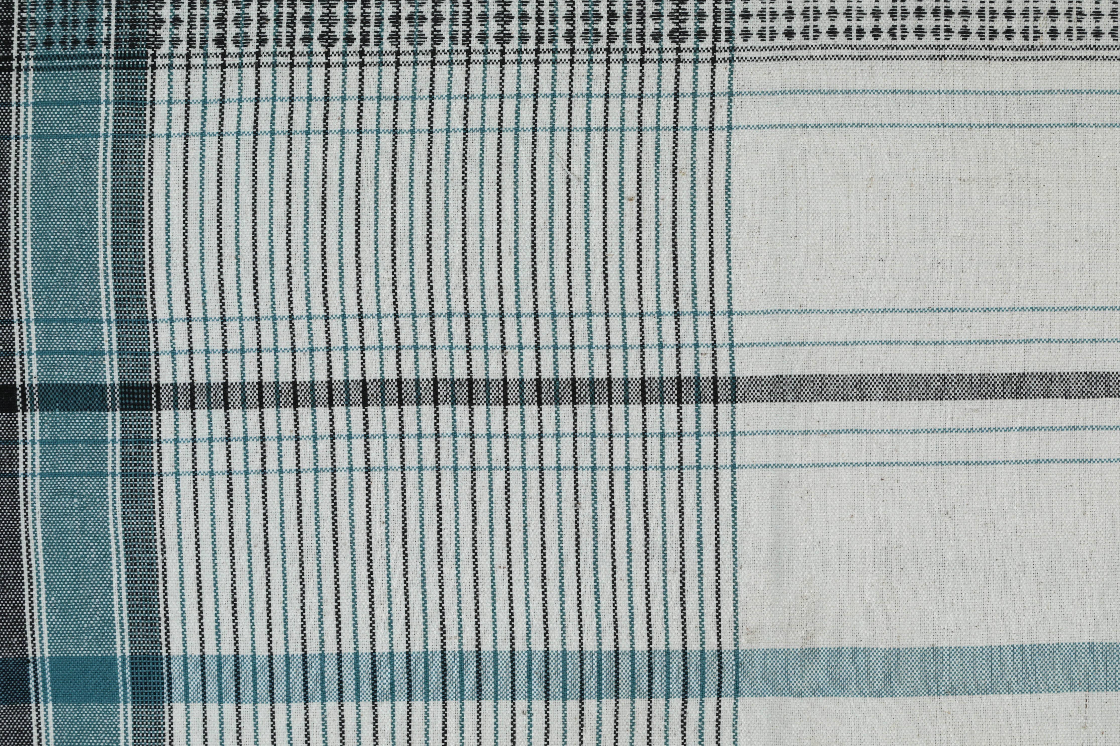Kala naturally dyed organic cotton from Gujarat, India. Hand loomed using traditional Indian textile techniques to produce extra weft woven stripes and plaids. This ivory, slate blue and black bedcover has added hand-knotted tassels.