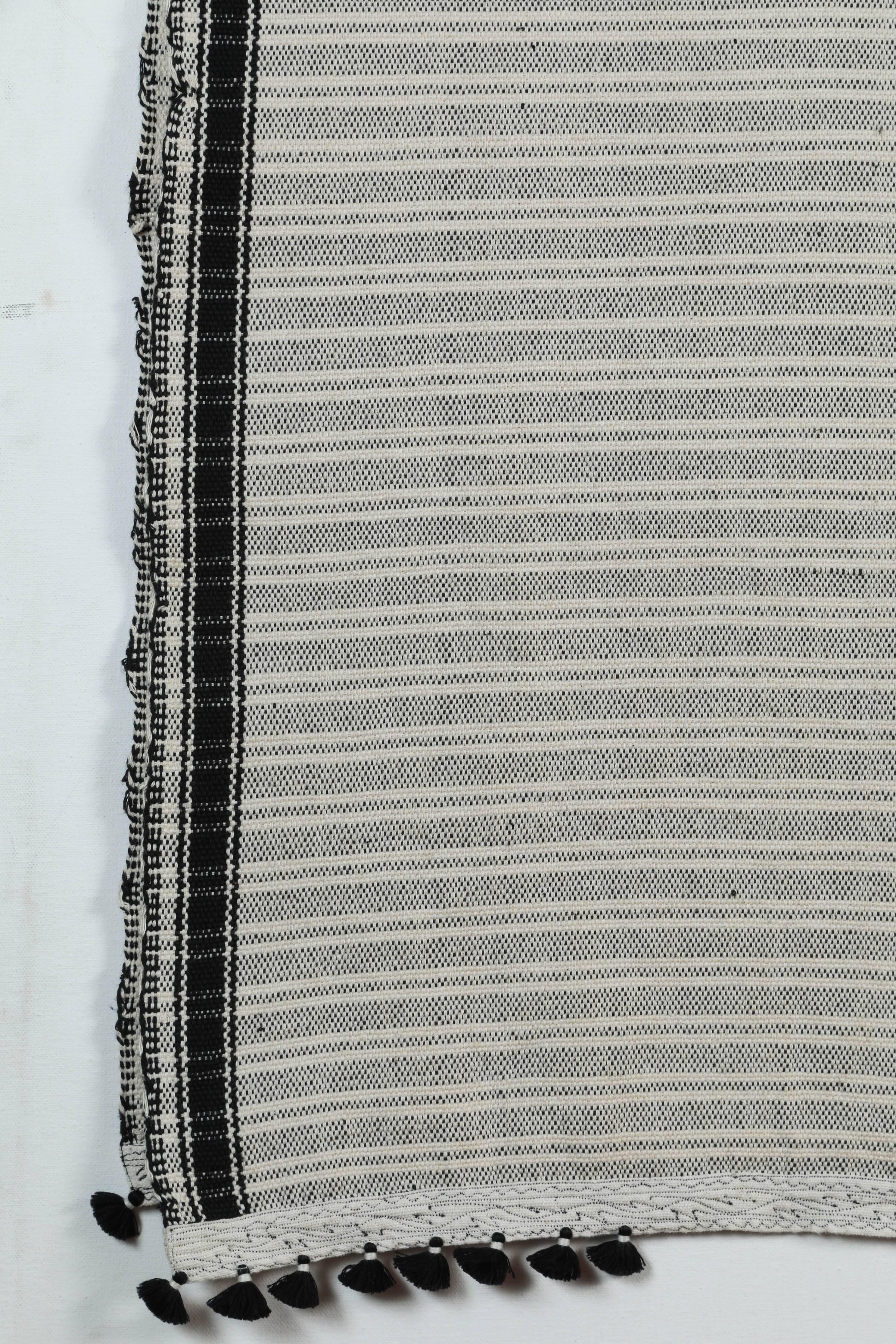 Kala naturally dyed organic cotton from Gujarat, India. Hand-loomed using traditional Indian textile techniques to produce extra weft woven stripes and plaids. This black and white bedcover has added hand-knotted tassels.