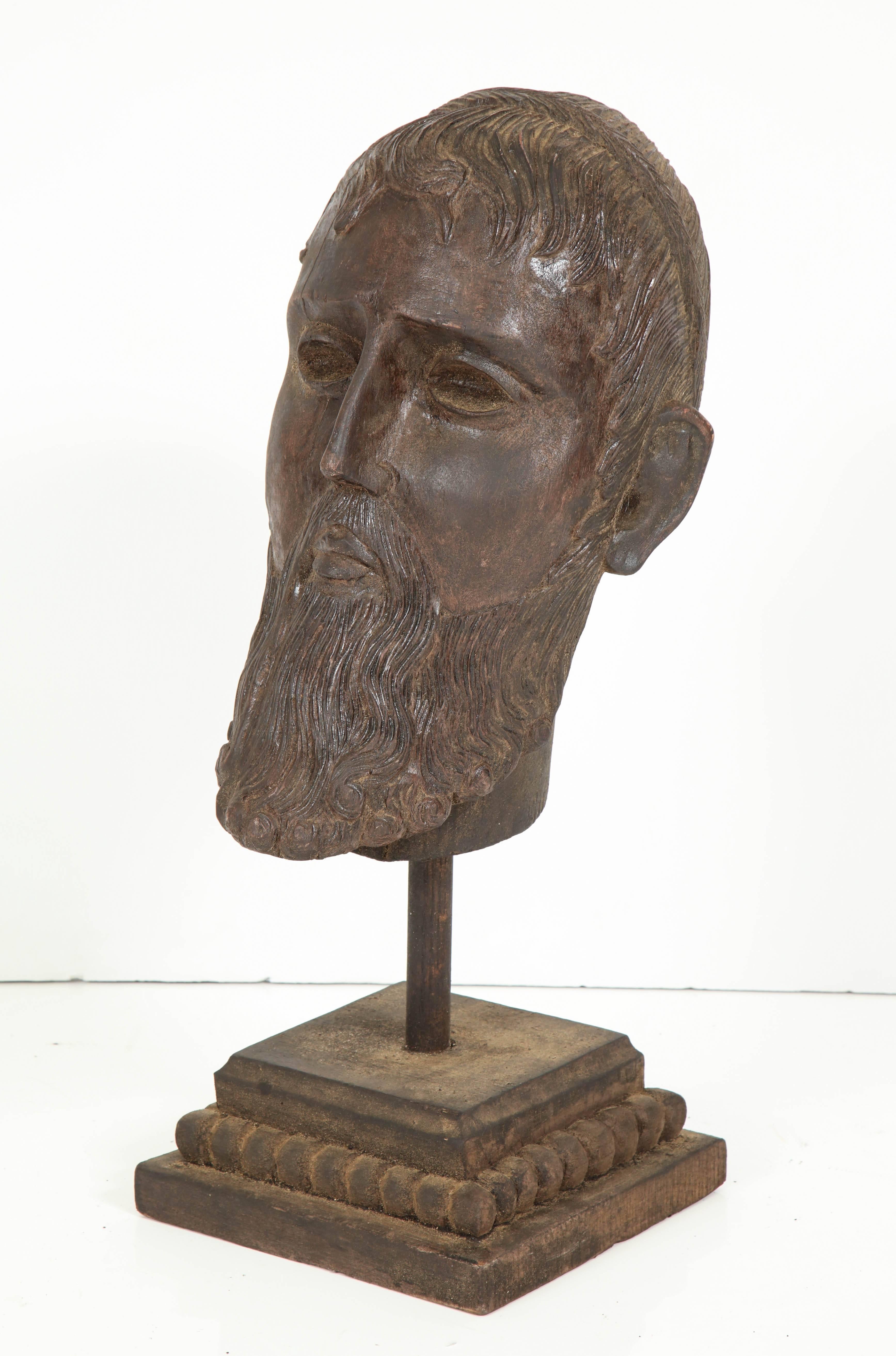 A large, lifesize head carving in the style of Classic Greek figures. The head appears to have been removed from a statue and paced on a more recent base. I think the head is late 19th century possibly.