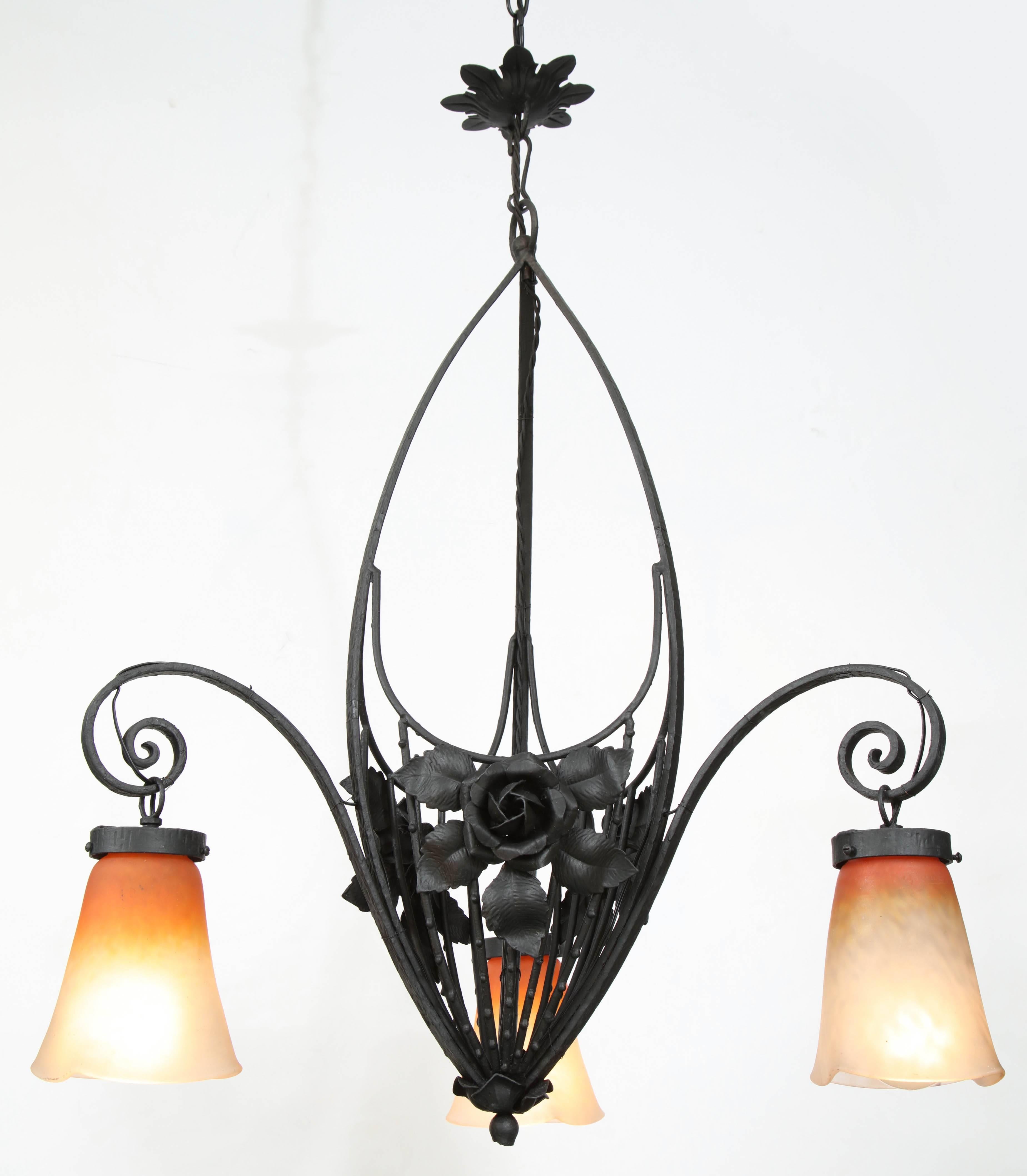Art Nouveau lacquered metal chandelier with floral detail and orange and white vaseline shades, signed Schneider.