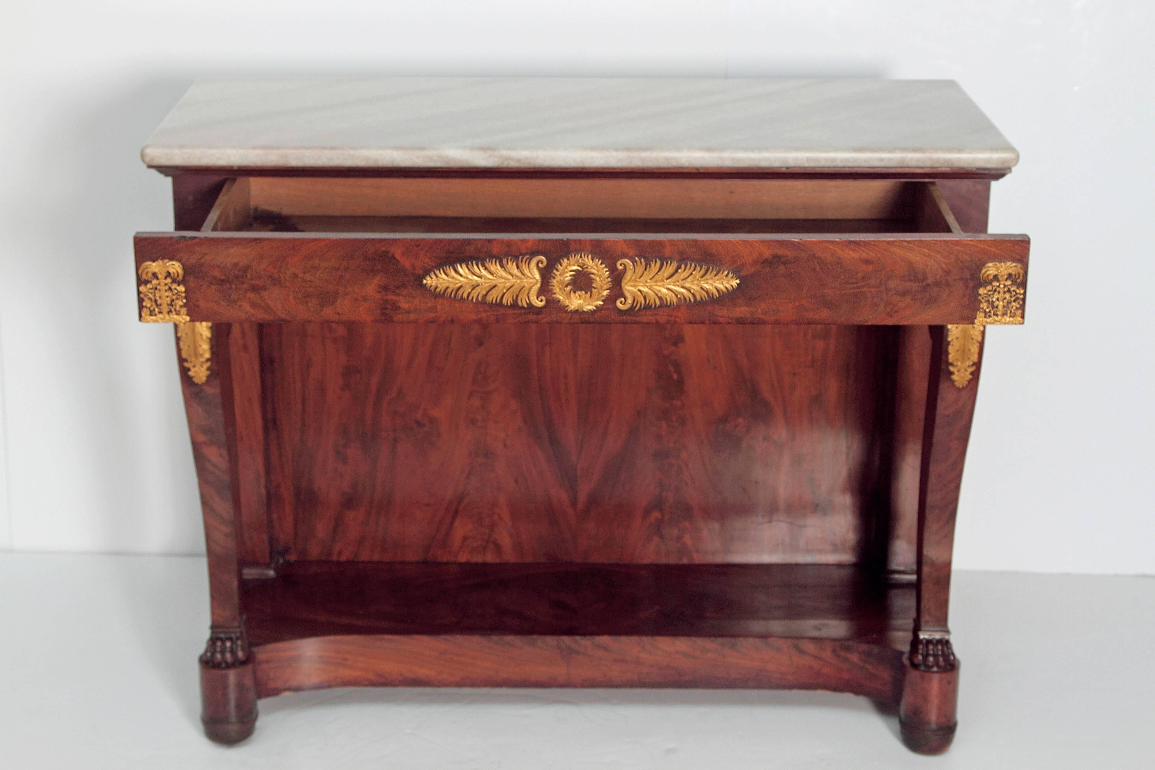 An elaborate early 19th century German neoclassic period console. Bookmatched mahogany with grayish white marble top. Curved legs with ormolu palm trees and grapevines above acanthus leaves at knees and paw feet. Wreath and palm leaves centre apron.