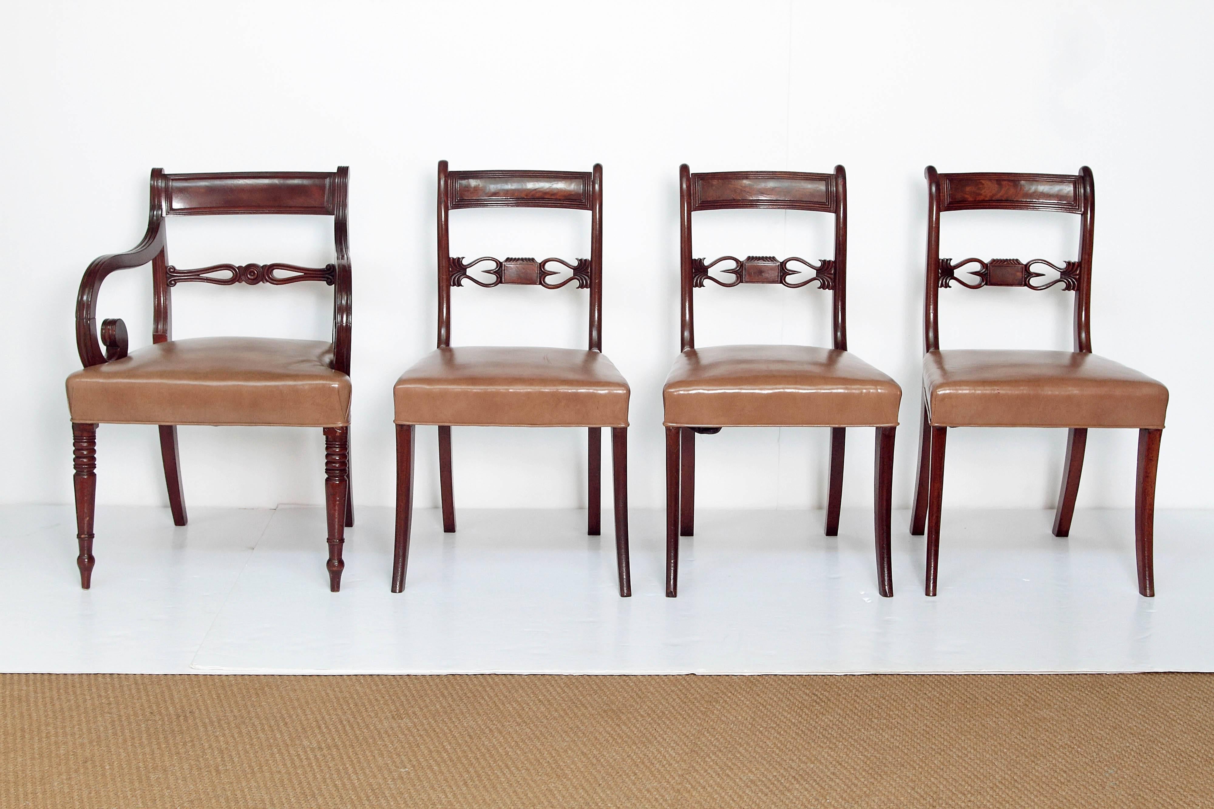 A set of eight English Regency dining chairs, six sides and two hosts. Top rails have linear rim and open carved center back support. Hosts have curled arms and turned legs. Beige leather upholstered seats.

Dimensions of Host Chairs:
32 inches