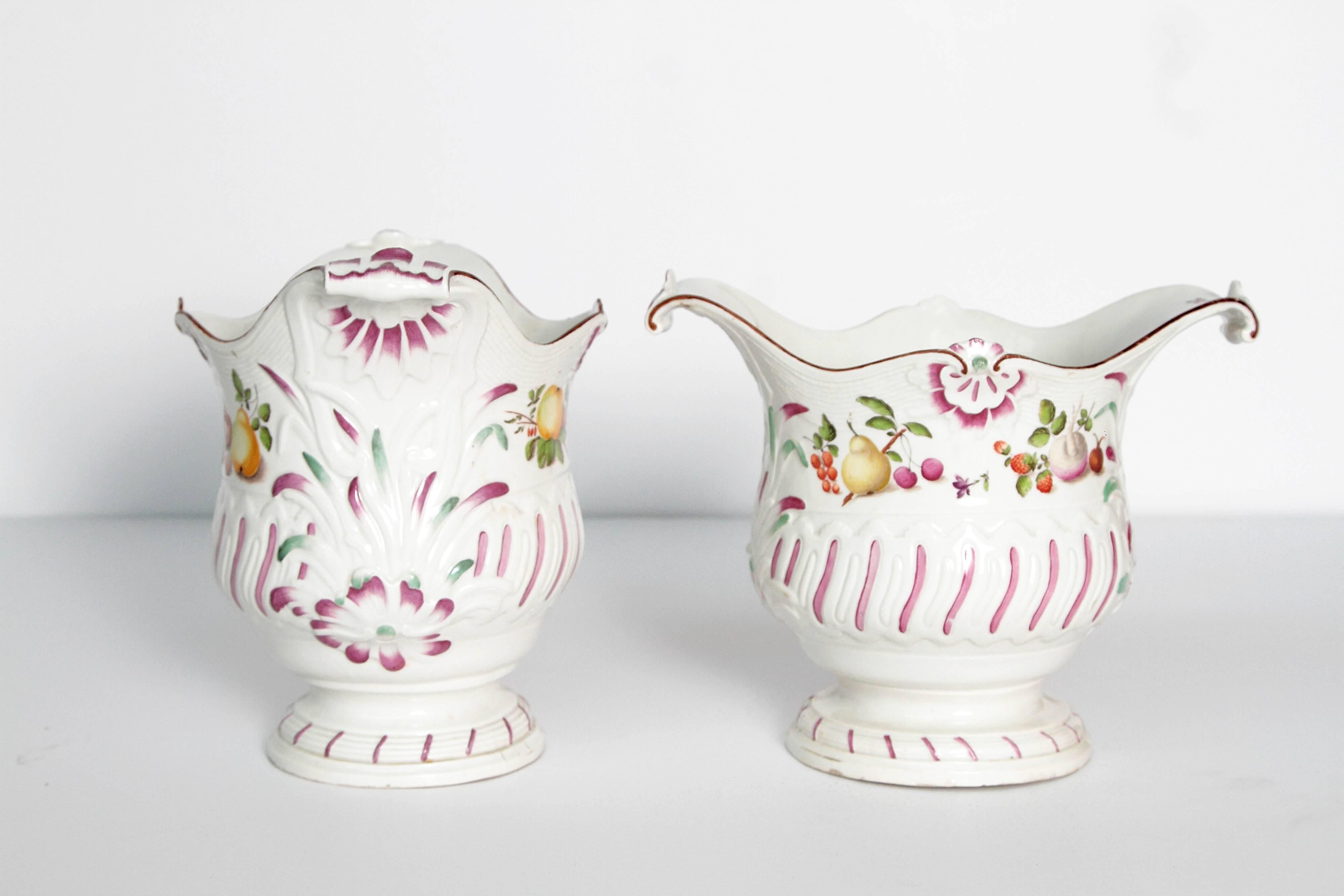 Pair of Vienna cachepots in white with raised decoration; painted with fruits and flowers and trimmed in pink.