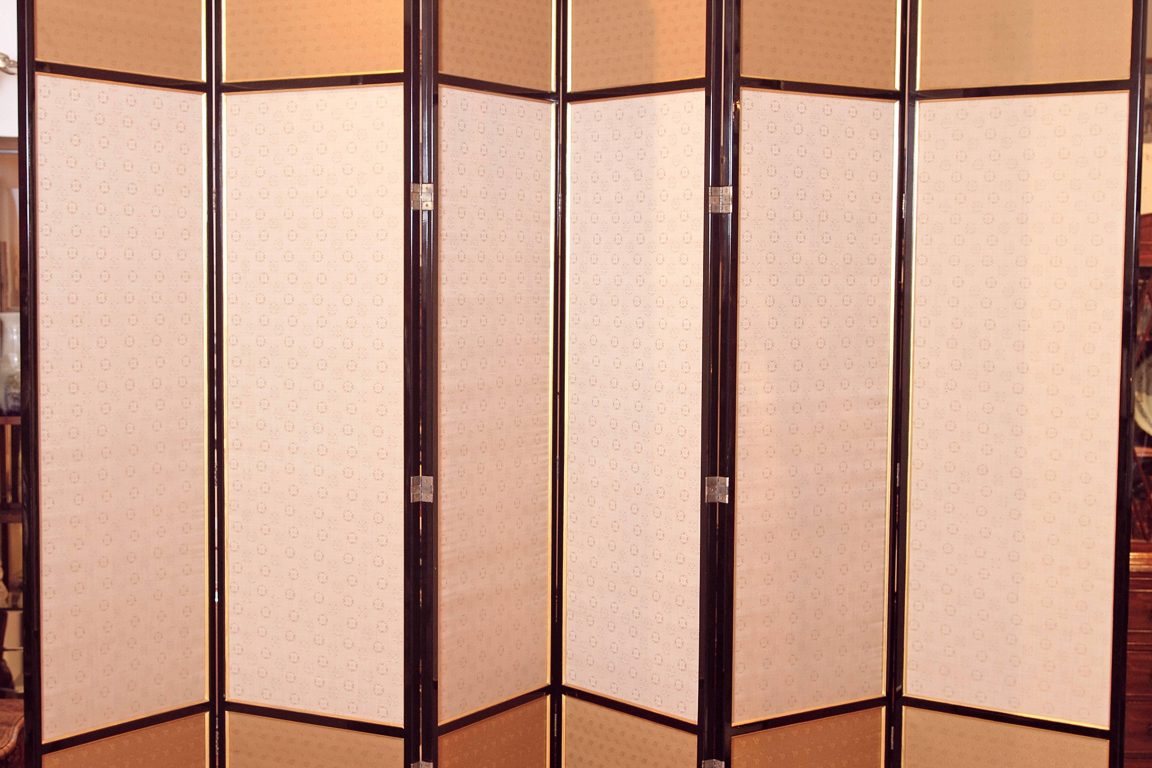 A large six panel black lacquer framed screen with delicately patterned beige and tan silk on front and greige fabric on reverse.

Each panel is 24 inches wide.