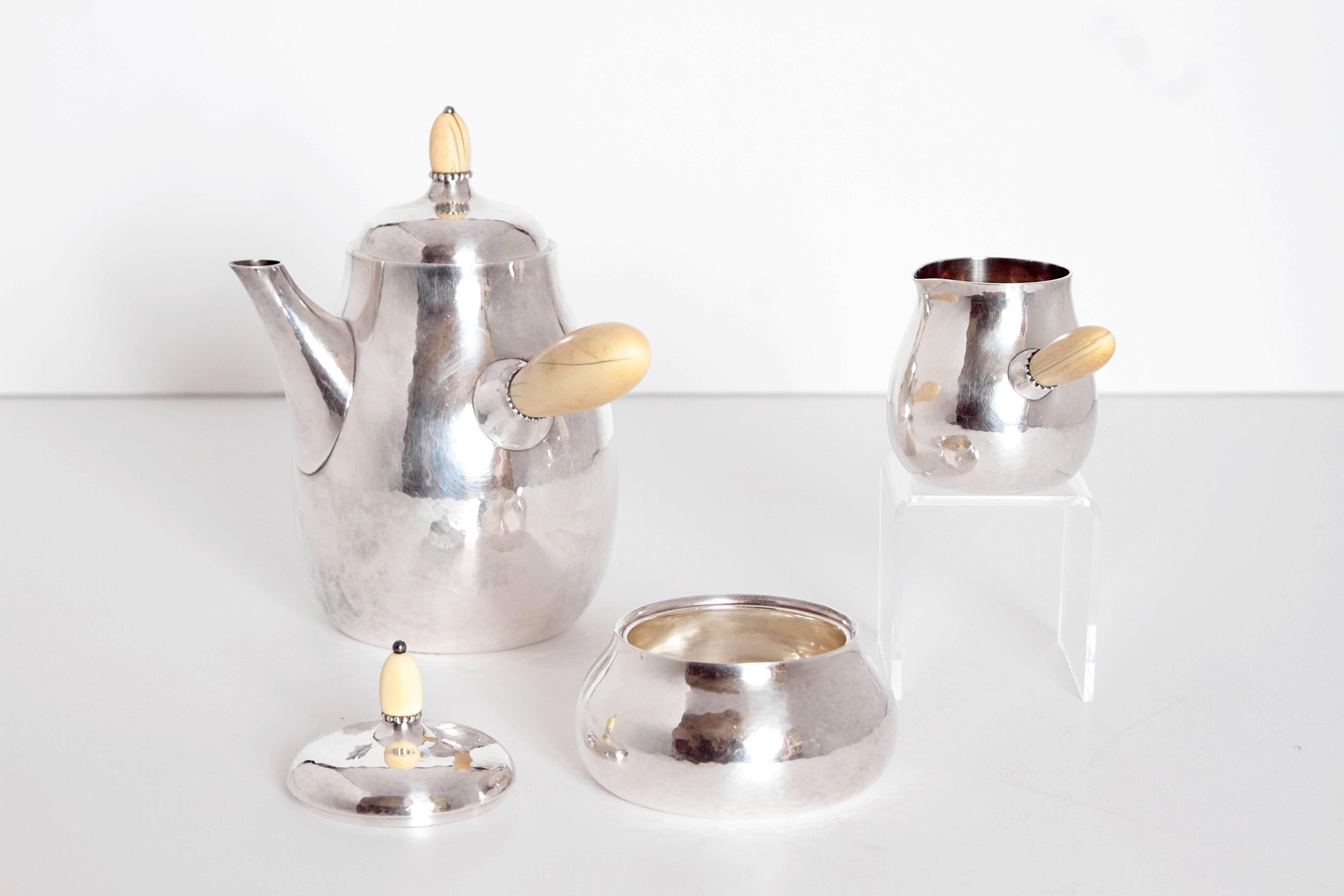 A Georg Jensen coffee set of silver with pot, sugar and cream jug. Bone handles and finials on lids. Stamped A. E. F. Sterling, Denmark

Measures: Coffee pot: 7 inches high x 7.50 inches wide x 4.25 inches deep
Creamer: 2.50 inches high x 4