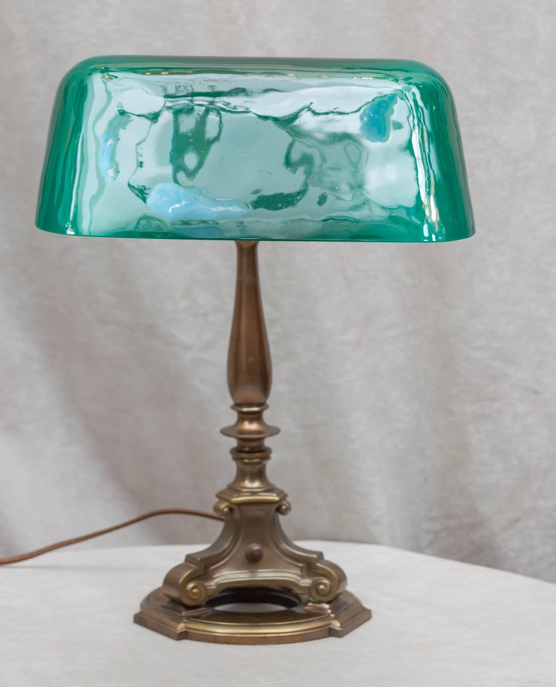 This signed Emeralite desk lamp is several cuts above the standard model. First off the shade is ten inches wide; the overwhelming examples are eight inch width. This has the glass diffuser under the shade to soften the light, and to top it off the