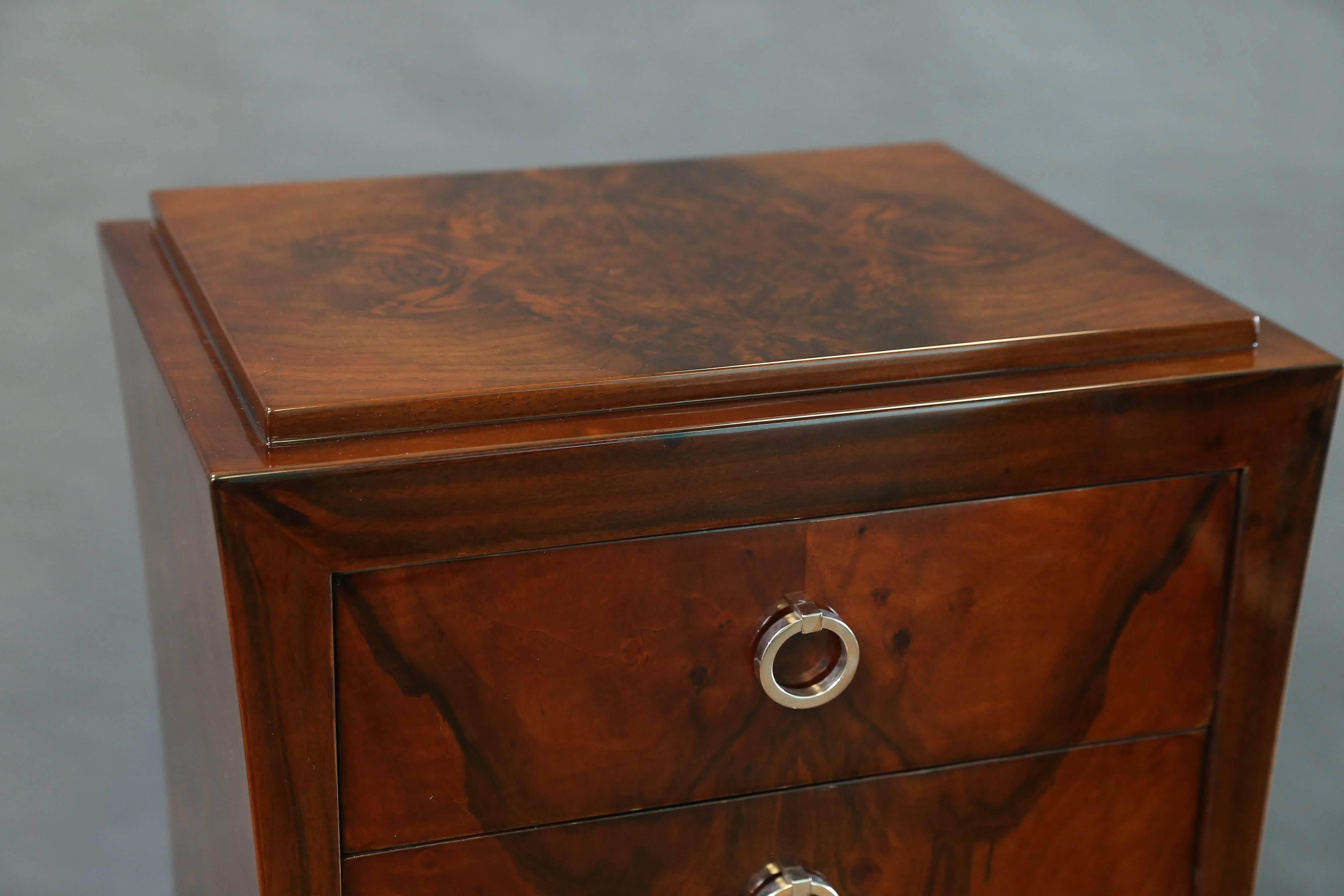 La cassettiera è realizzata in pregiato legno di noce. Ha quattro cassetti stretti con maniglie rotonde cromate e un cassetto largo sul fondo. Il petto è sollevato dalla base rettangolare. I pannelli laterali altamente lucidati mostrano la bellezza