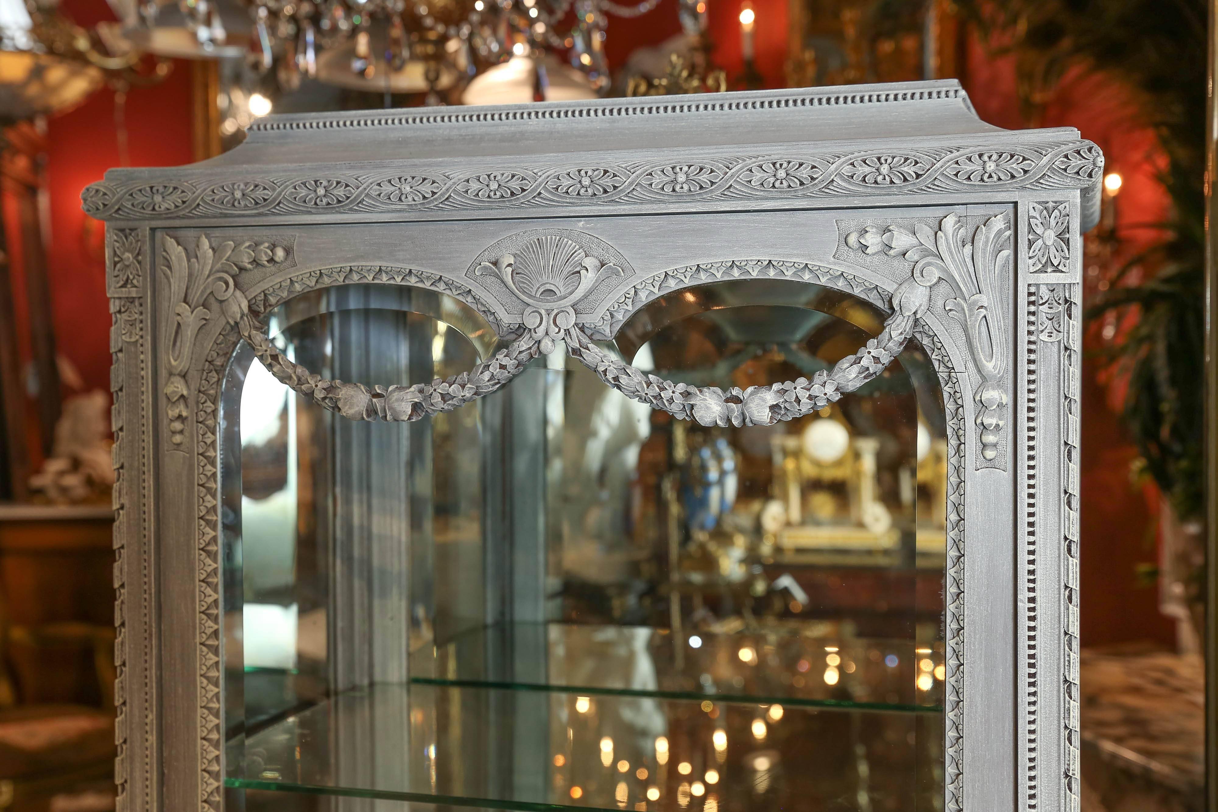 Elegant Louis XVI style vitrine or display cabinet, late 19th century that has
Been painted in grey with lighter highlights. Pretty Foliate garland
Enhances the upper portion of this piece. The back is mirrored and
Displays the contents