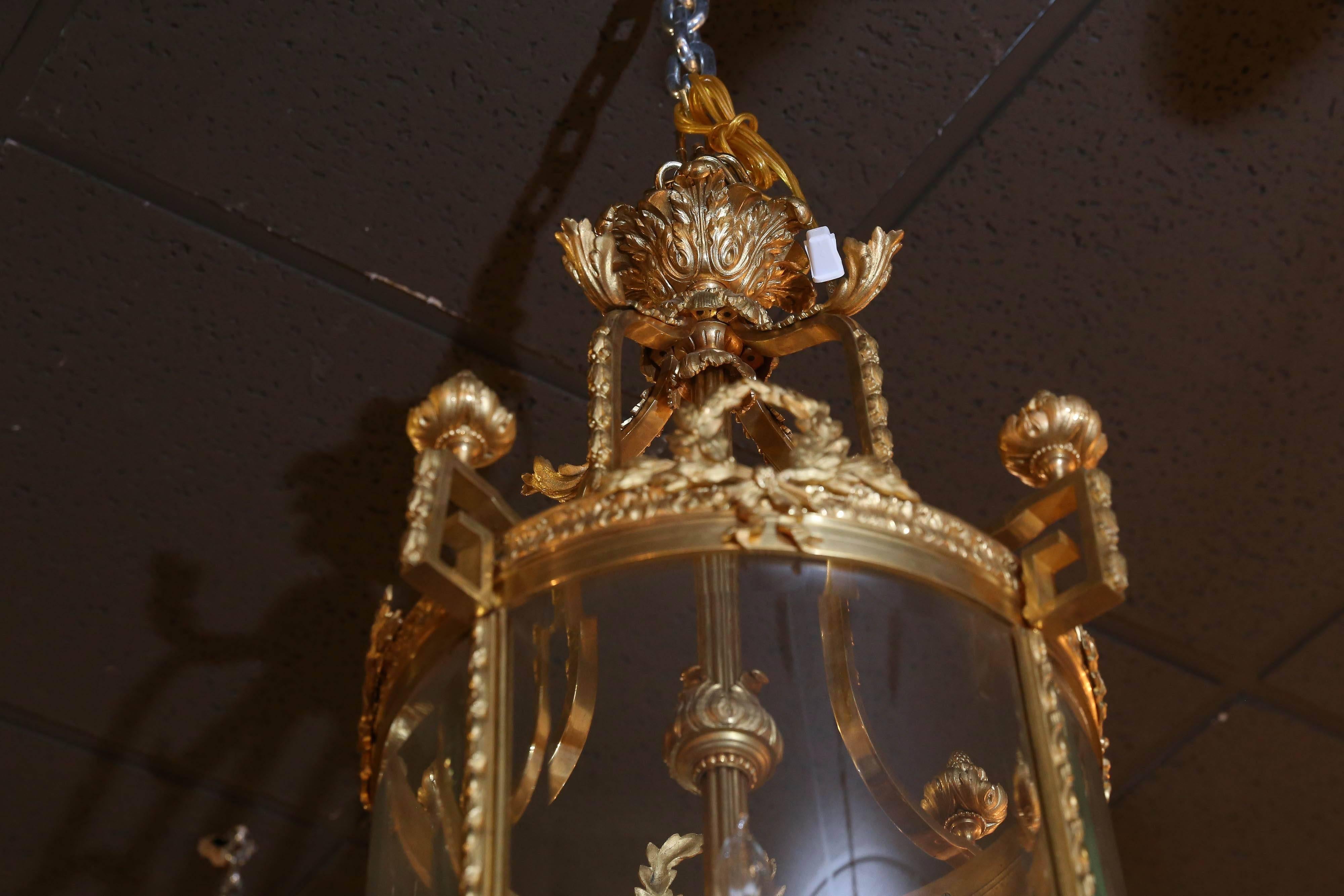 Beautiful gilt bronze frame, lantern style chandelier having four candle/ lights
Stemming from a central post. In fine working order a foliate wreath centers
Between the sections at the upper frame. A gilded pendant decorate the top
Of each