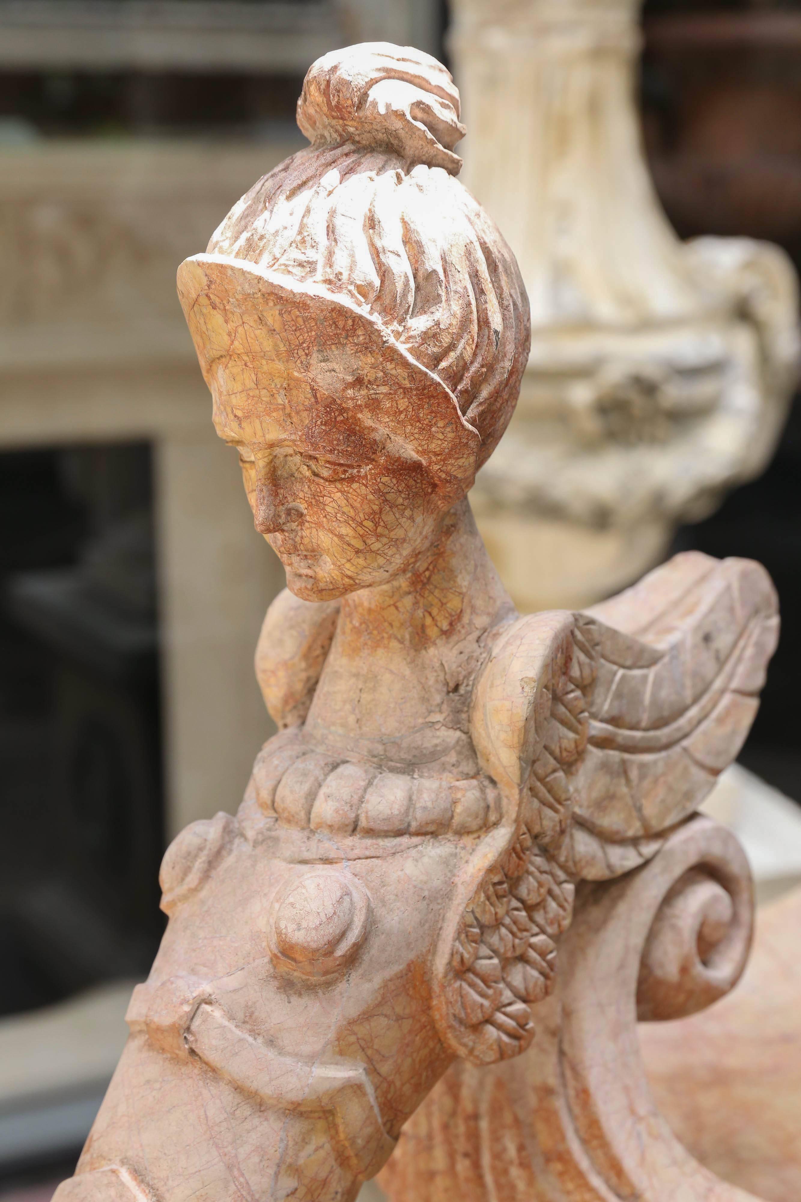 Pair of coral colored ewer statues carved in marble in the form of winged
Females set on a square base.