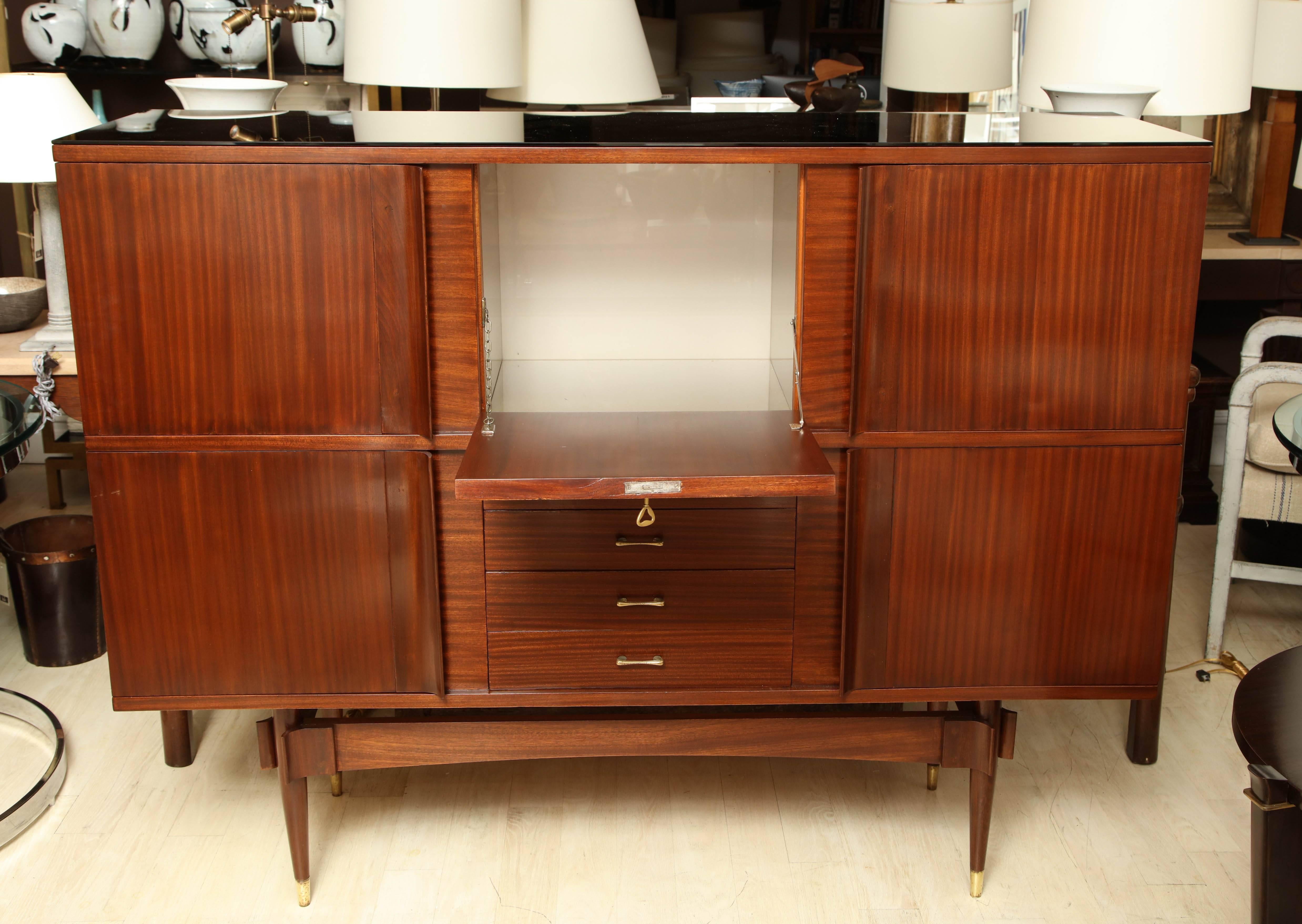 Four-door quarter sawed sapele wood cabinet with three drawers, a drop down bar section, four cabinets, and mirrored glass top. Original brass hardware.

Available to see in our NYC Showroom 
BK Antiques
306 East 61st St. 2nd fl.
New York, NY 10065