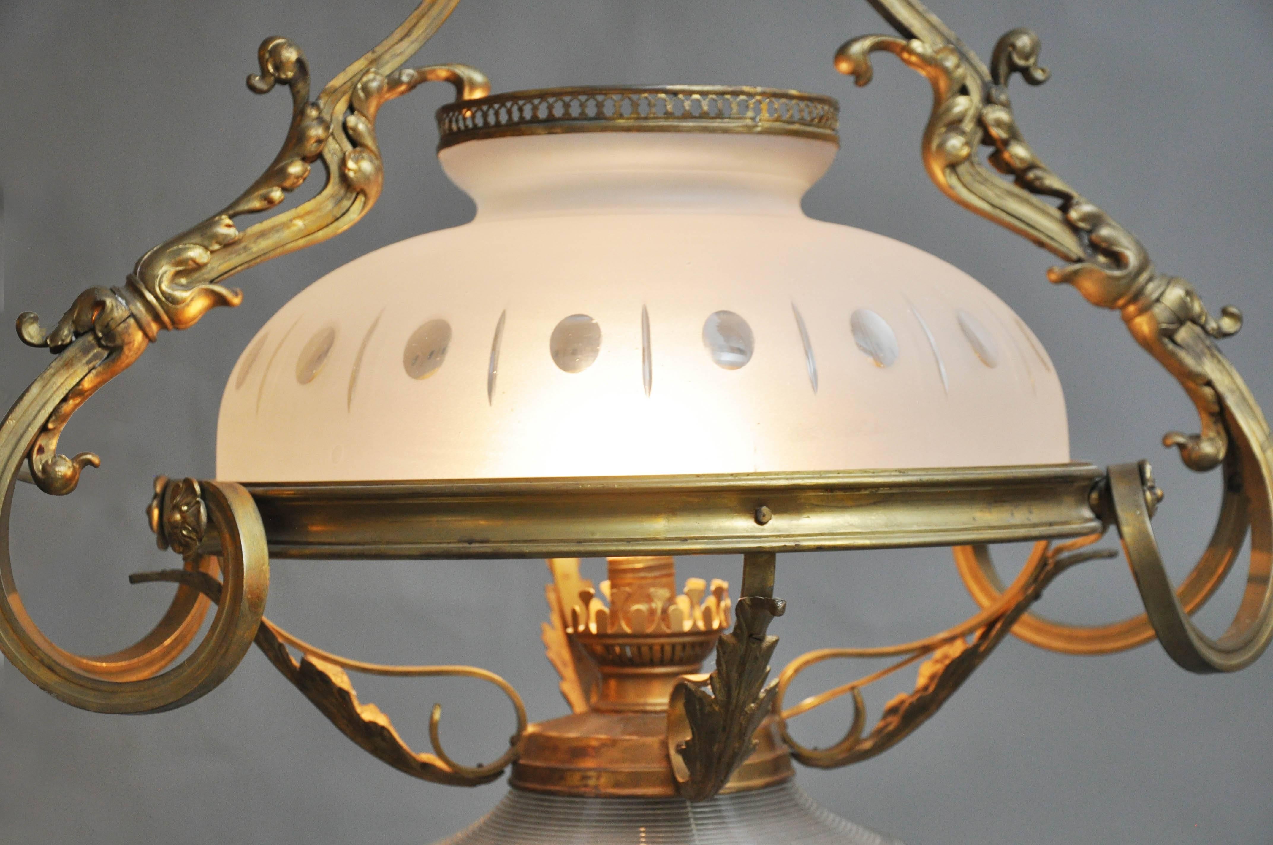 19th century French Rococo mercury bronze oil lamp chandelier originally oil converted to electric. Elaborate gold bronze scrolled frame with acanthus leaf decoration supporting a central oil lamp with dome shaped frosted acid etched shade and