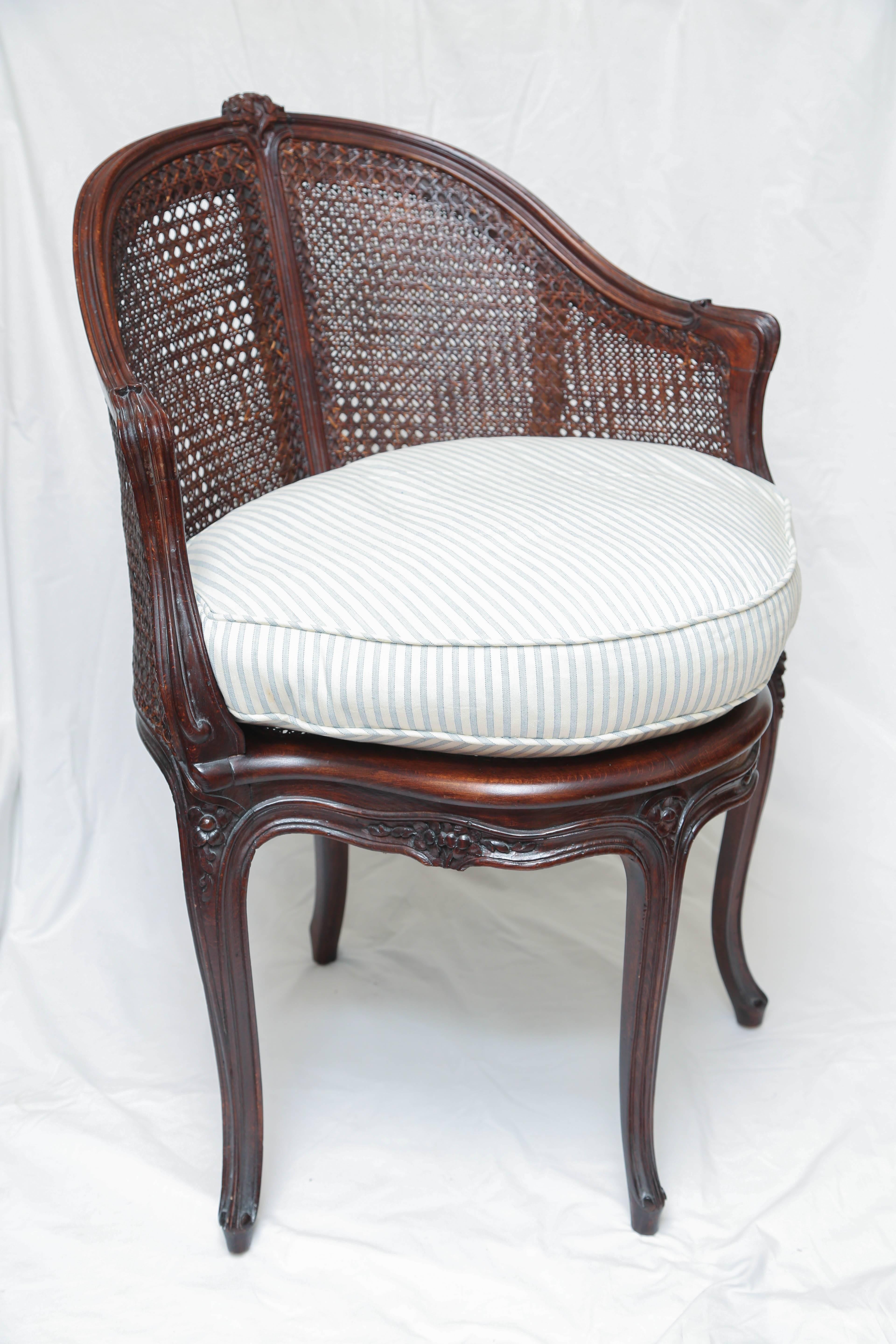 Single French caned armchair with down cushion and blue and white ticking fabric.