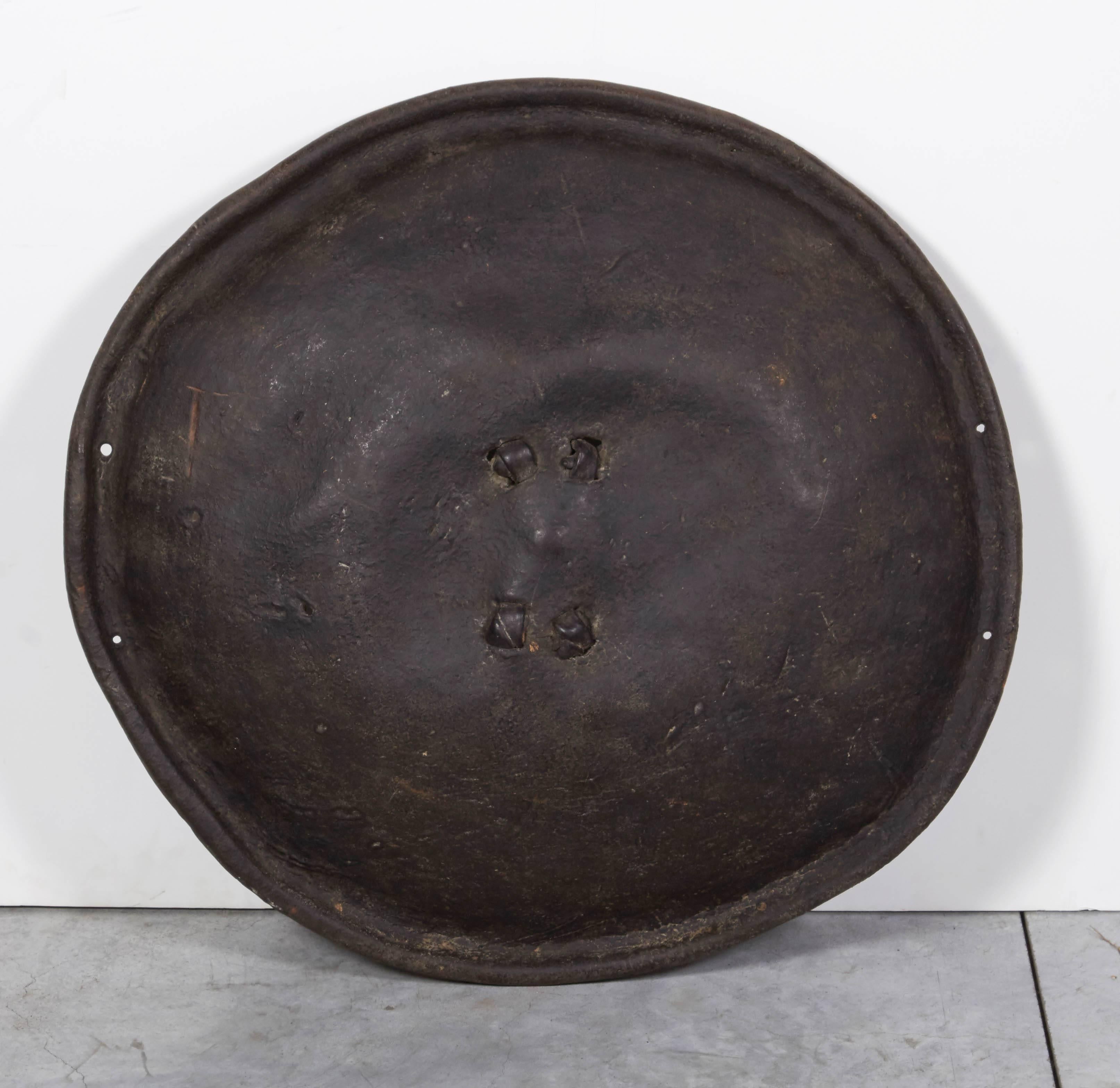 An early 20th century Ethiopian animal hide shield with leather knots at the centre securing the crudely formed handle. This piece has significant and attractive wear showing it's age and use. Works very well either hanging on a wall, or mounted on
