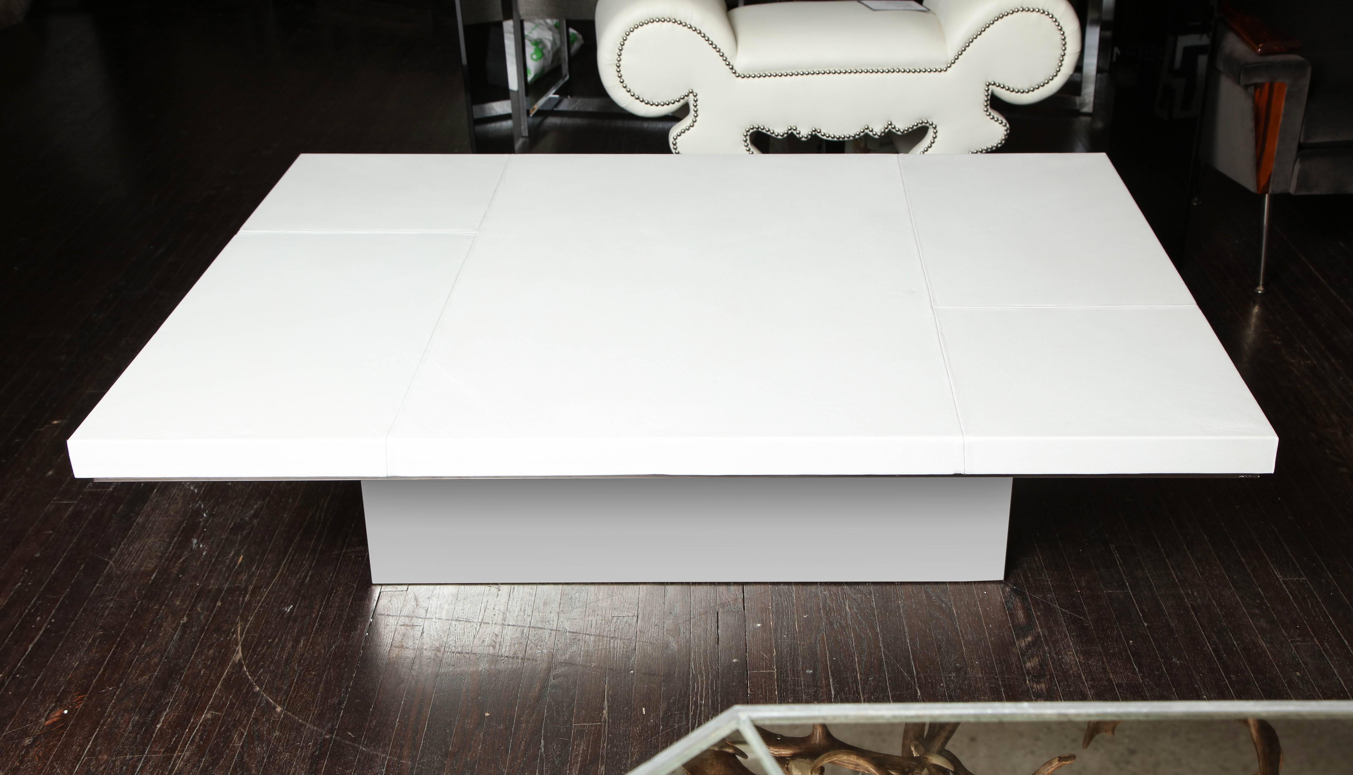 Table à cocktail chic en cuir blanc avec détails de surpiqûres sur une base en acier inoxydable miroité.