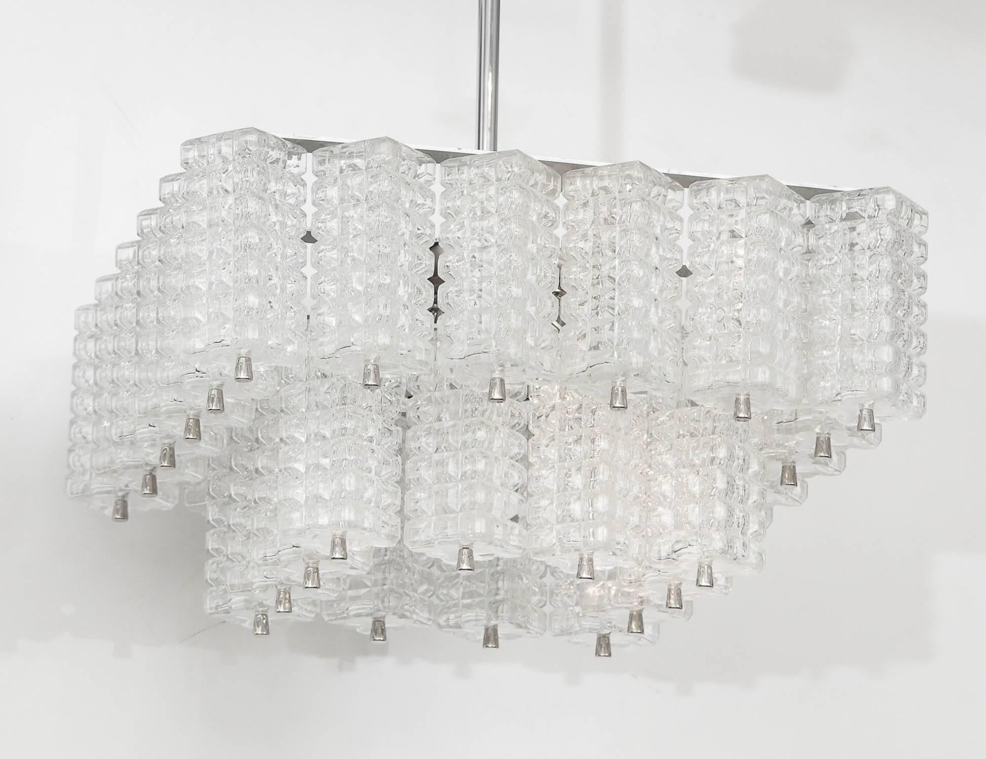 Lampadario modernista con due livelli di elementi in vetro rettangolari sfaccettati sospesi su una struttura in nichel spazzolato. Ricablata per essere utilizzata negli Stati Uniti con lampadine di tipo lampadario.