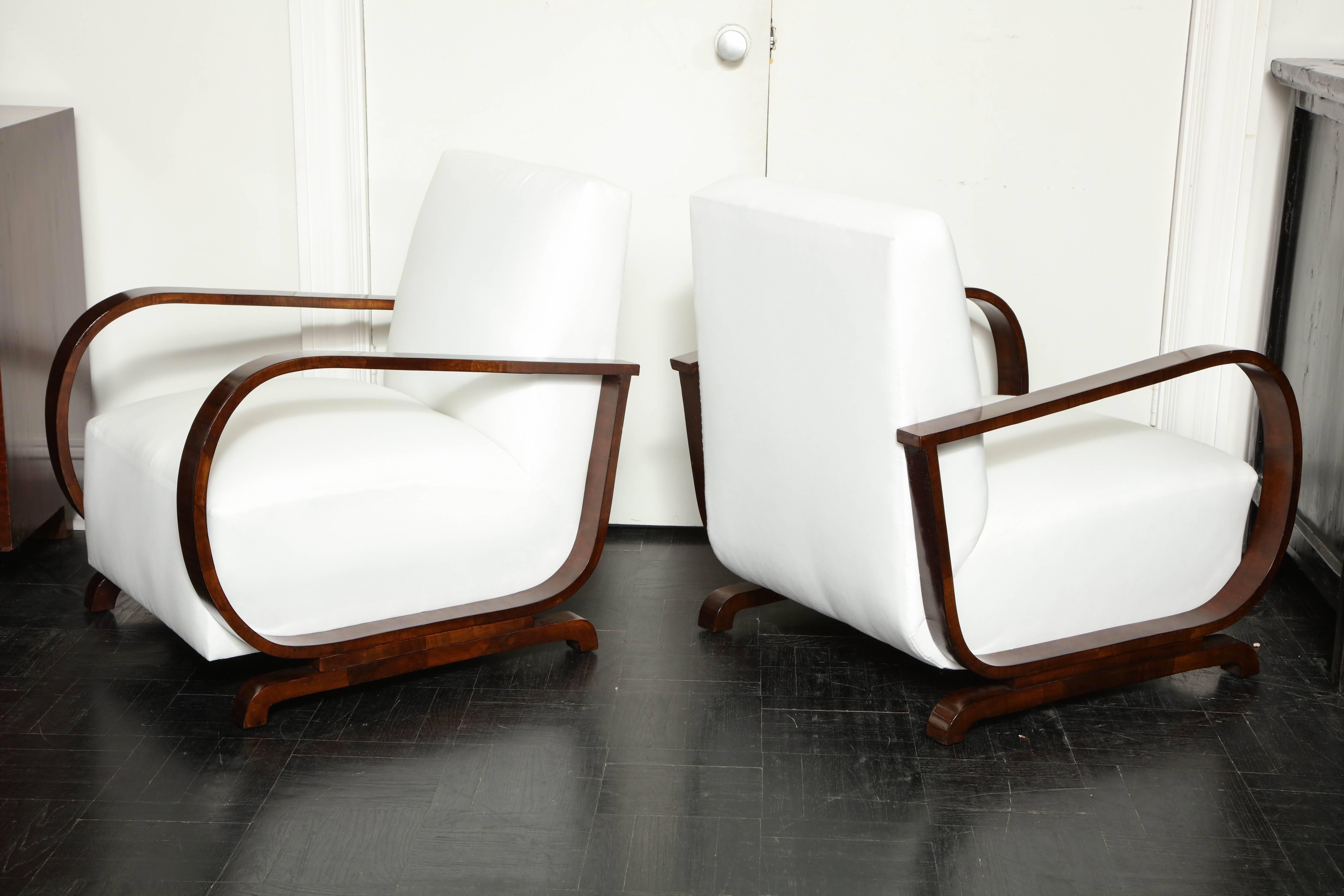 A pair of elegant Mid-Century teak armchairs with sloped backs and exaggerated 
