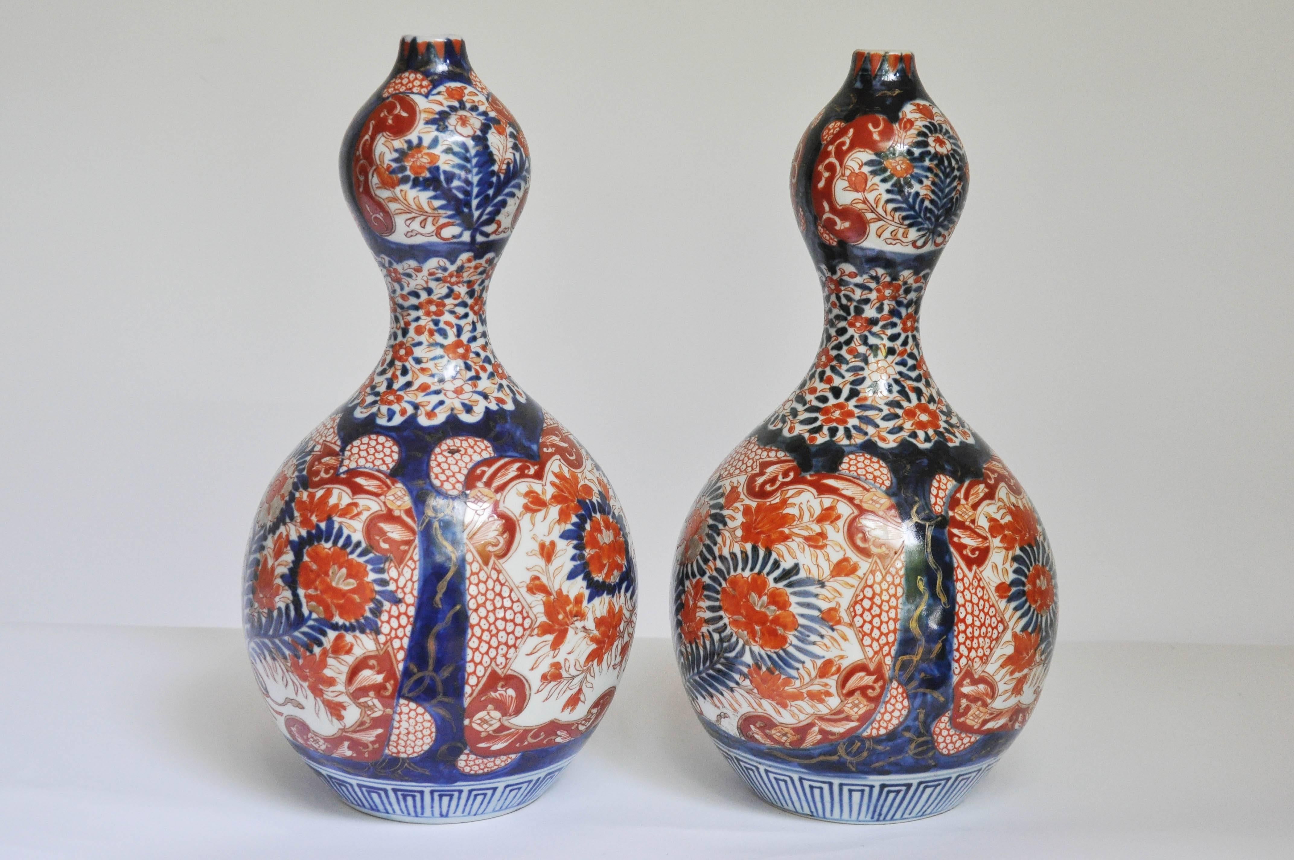An extraordinary very rare pair of Arita porcelain double gourd garnitures. Using the original Gosai pattern, each vase is a mirror image of the other both sides of the lower bulge are detailed with Arita-red glazed chrysanthemums and peonies all
