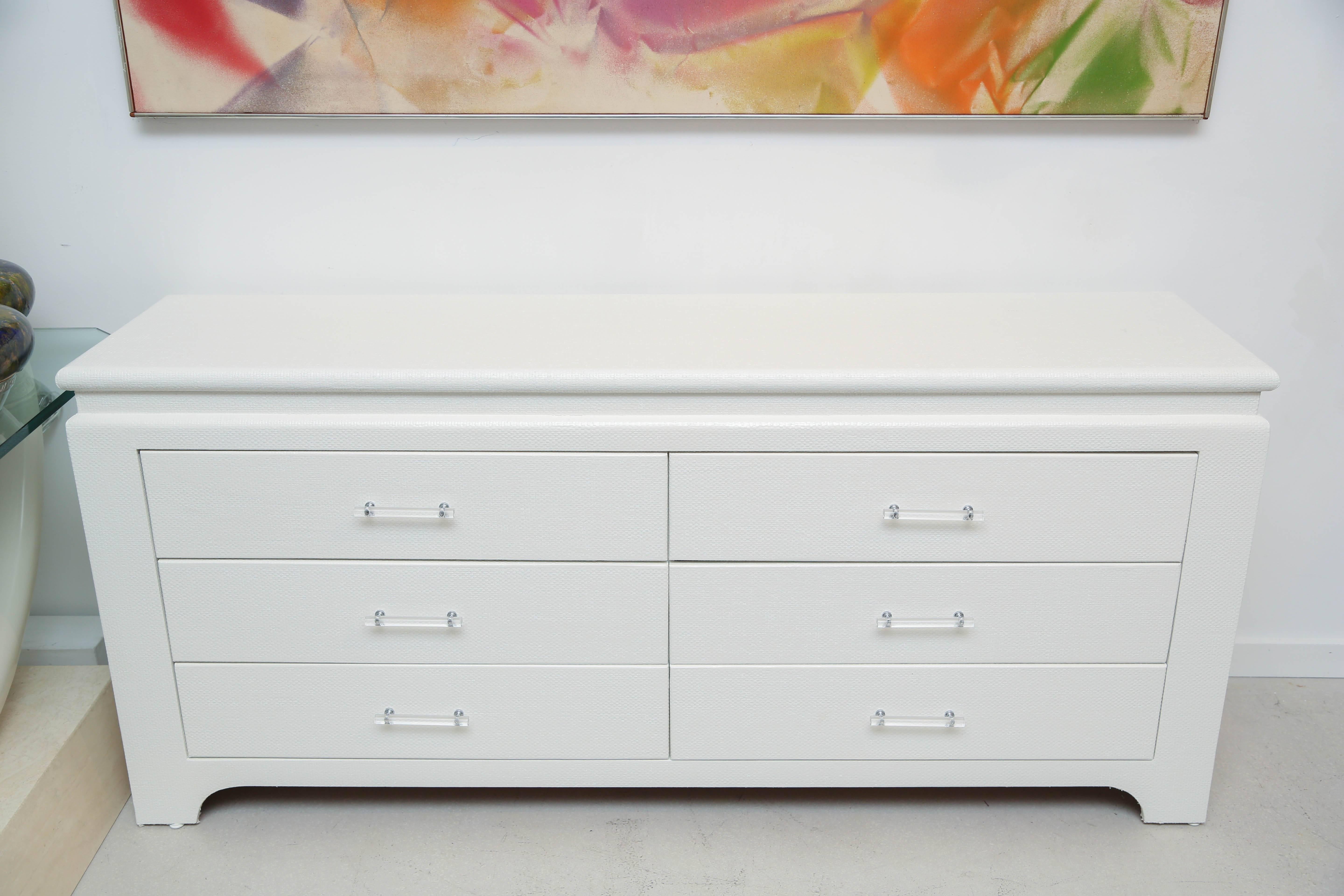 Mid-Century white lacquered grass cloth chest of drawers with Lucite handles. The chest has been professionally painted and showroom condition.