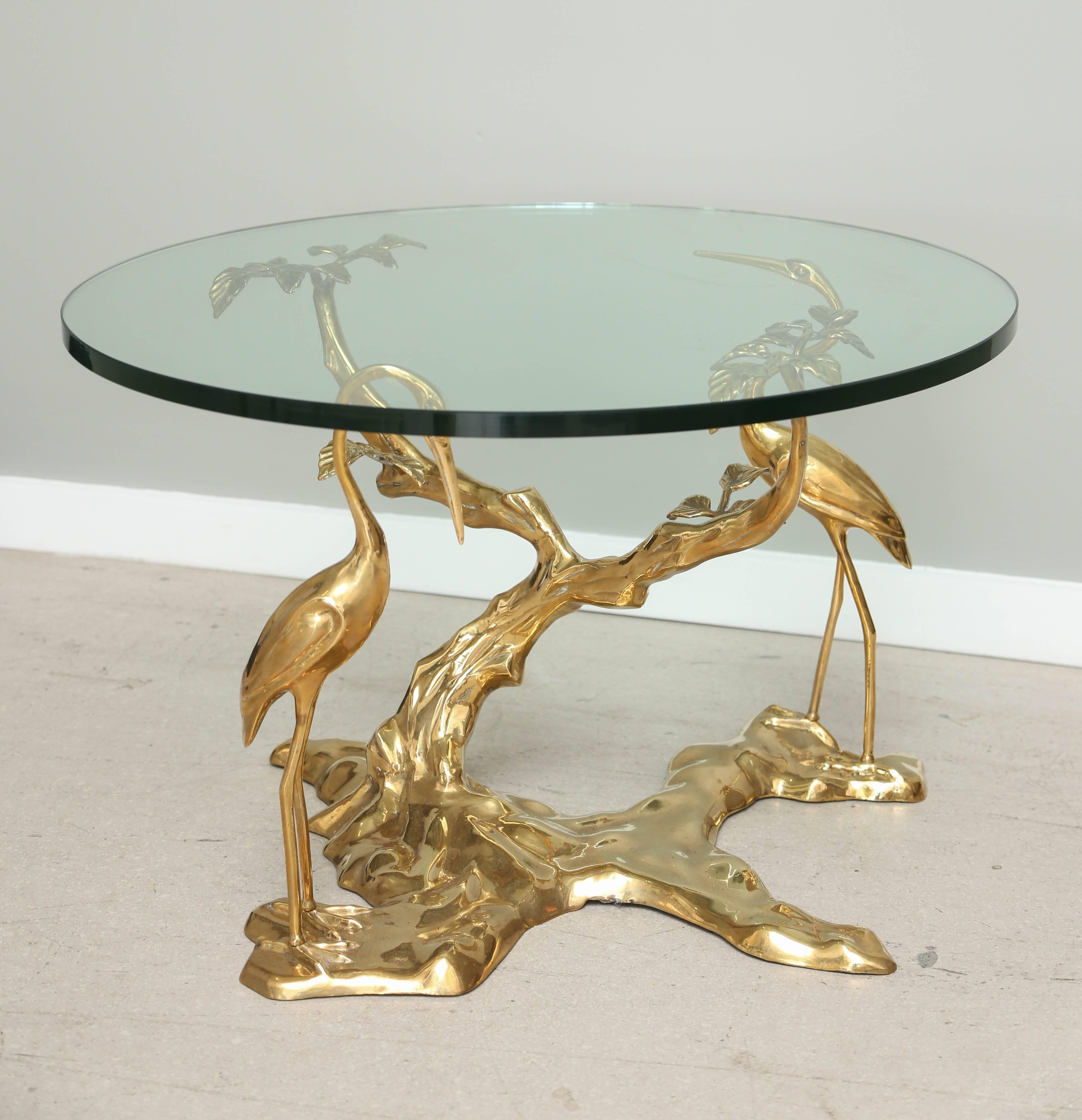 Sculptural bronze side table with fanciful bark and root system morphing into branch support with herons. The table has a circular glass top.