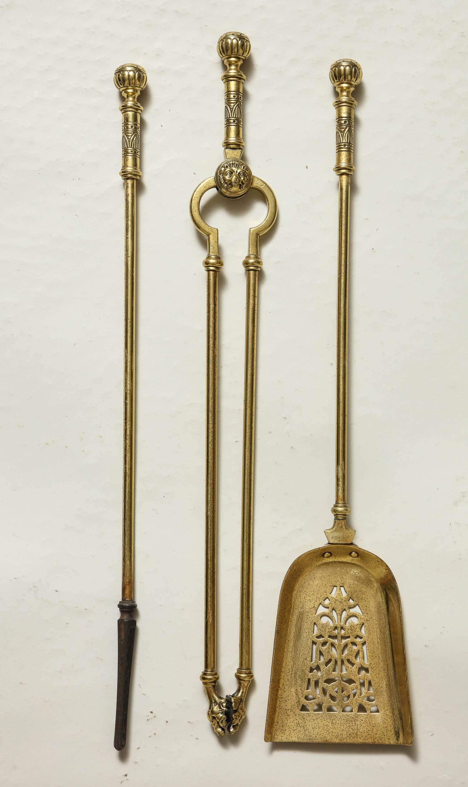 Good set of three mid-19th century English solid brass fire tools having suppressed ball finials with ribbed mount. The tongs with lion mask boss and paw grips, the shovel with pierced decoration.