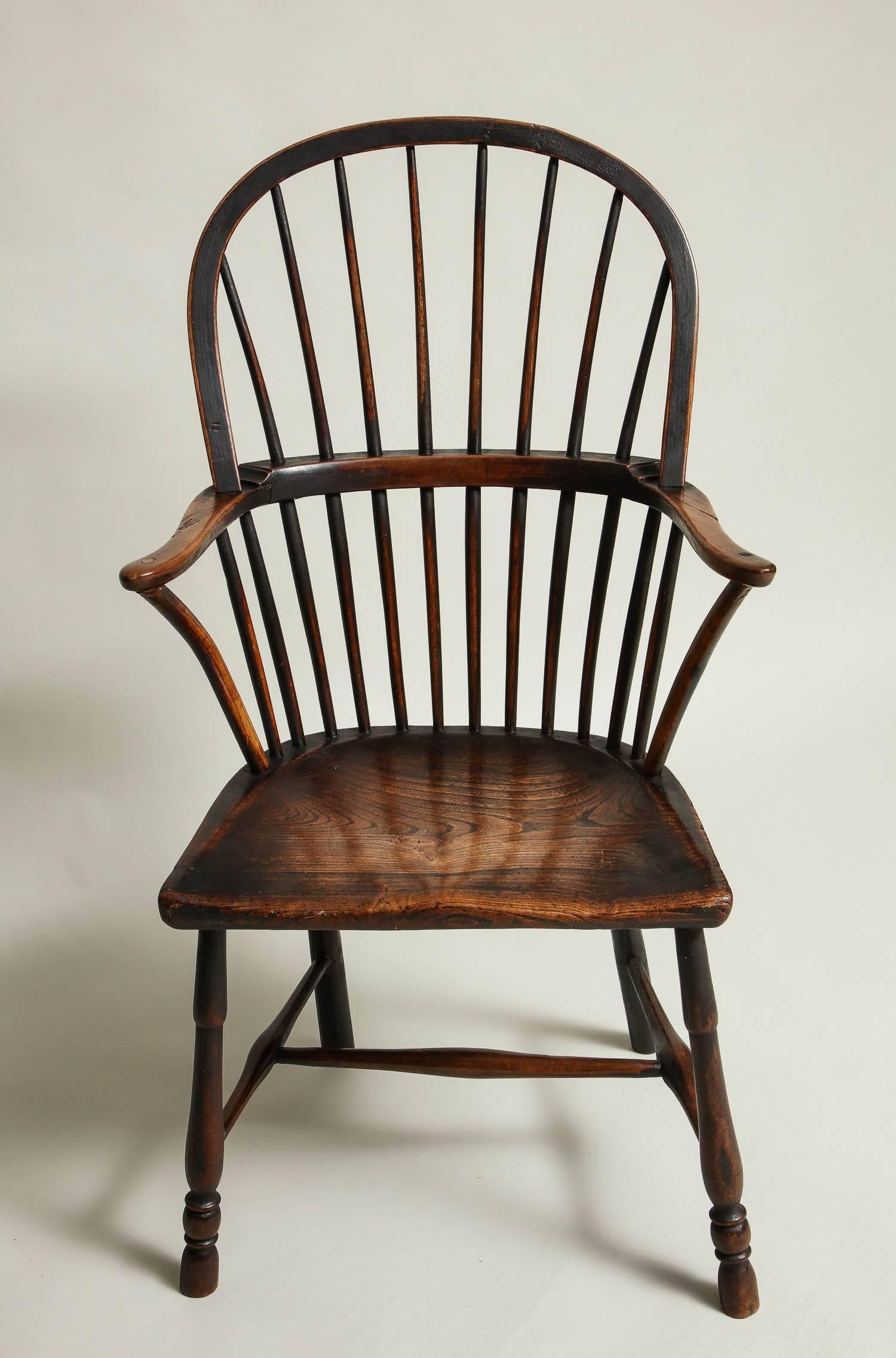 Fine 18th century, English hoop back Windsor armchair in ash, elm and fruitwood, the bent bow back with eight spindles supporting top hoop, the braced arm with stepped construction and supported by four additional spindles and bentwood struts on