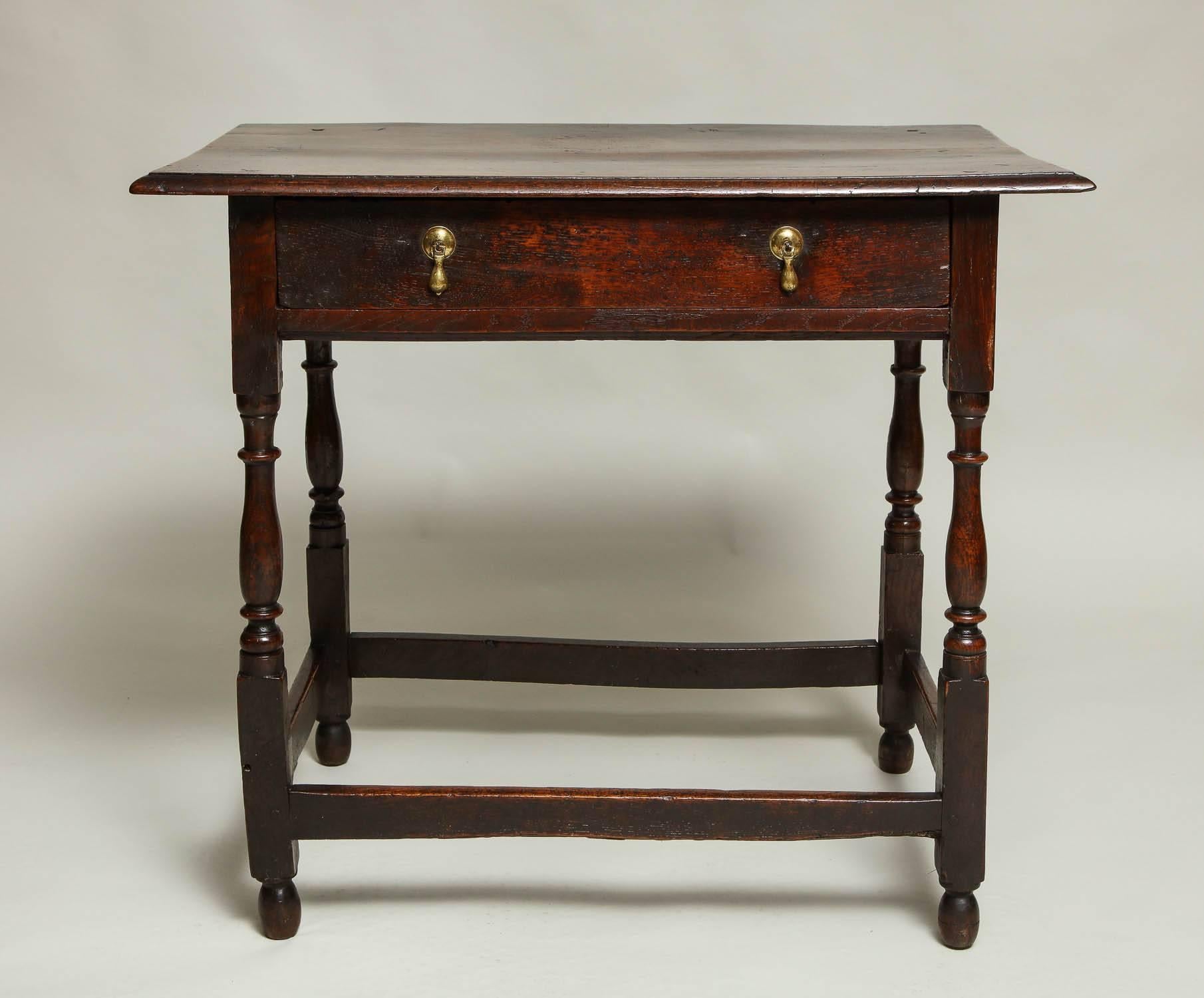 Queen Anne period English oak side table having a richly patinated thumb molded top over single drawer with early teardrop pulls, over balustrade turned legs joined by box stretcher and standing proud on original turned feet. The whole with
