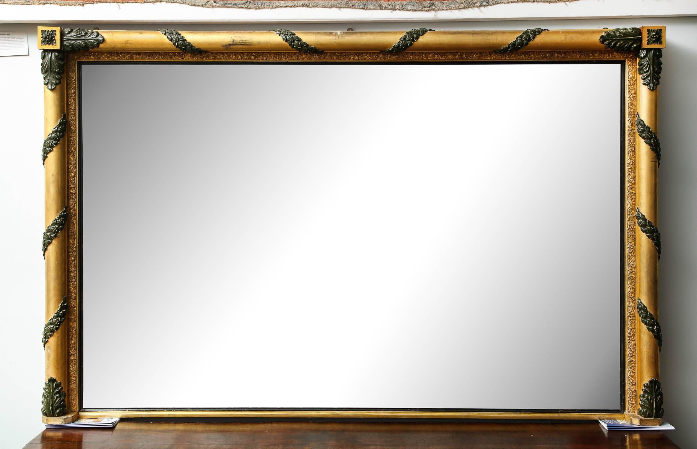 Very large early 19th century English gilt and painted wood overmantel mirror with carved acanthus leaf carved caps on the ends of the smooth gilt columns, the inner and outer border with gilt composition decoration, retaining its original mercury