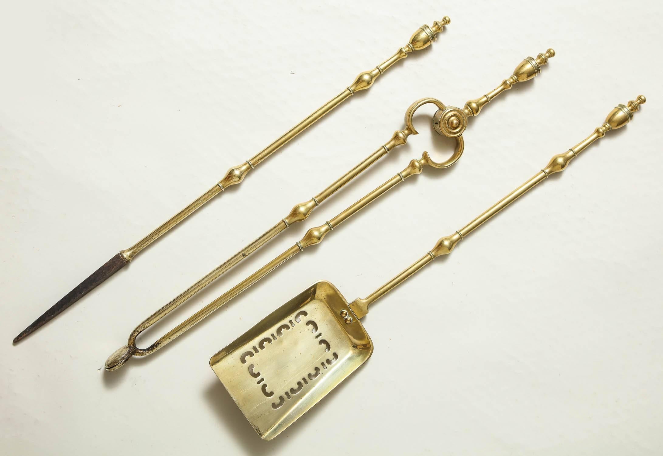 Fine set of George III brass fire tools having urn finials, swollen balustrade turned collars, the poker with iron tip, the shovel with pierced decoration, the set with good weight and balance and having elegant design.