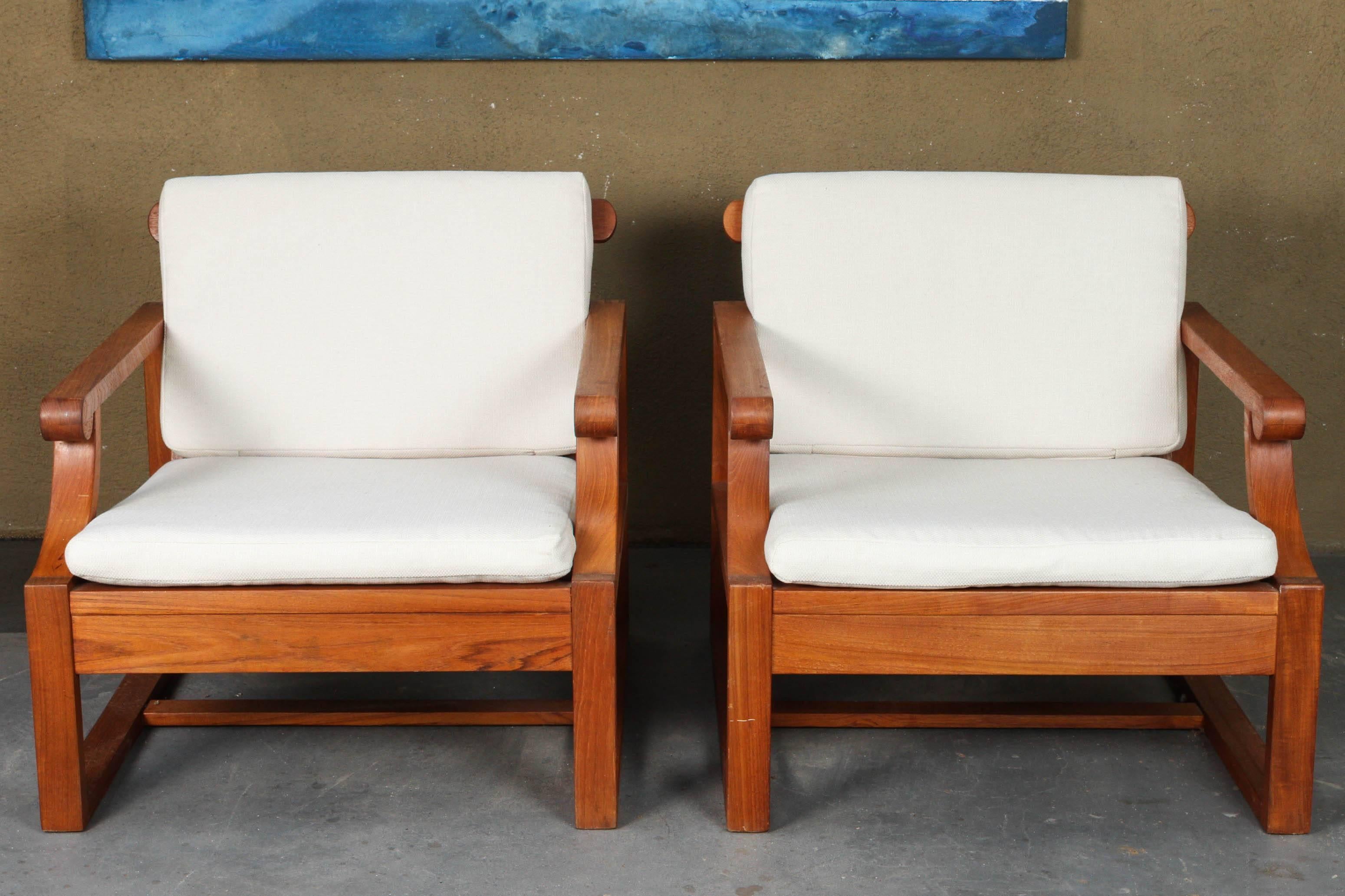 Spectacular pair of lounge chairs. Beautifully designed for both look and comfort. Could be used indoors and out. Rich warm teak base with white seat and back cushions.


