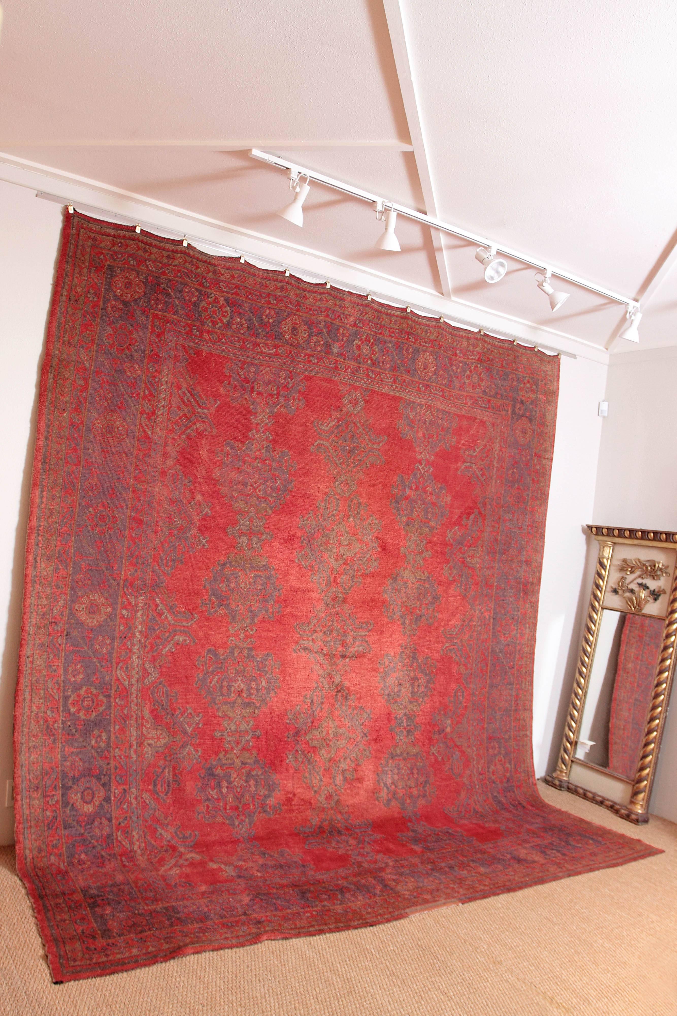 A late ottoman period Turkish Oushak rug, circa 1890 to 1910, with sylized geometric garden motifs. 
Persimmon colored field with bronze, cinnamon, and goldenrod colored yarns in the design, 
Turkey, Region of Anatolia.
Measures: 10’11” x 12’5”