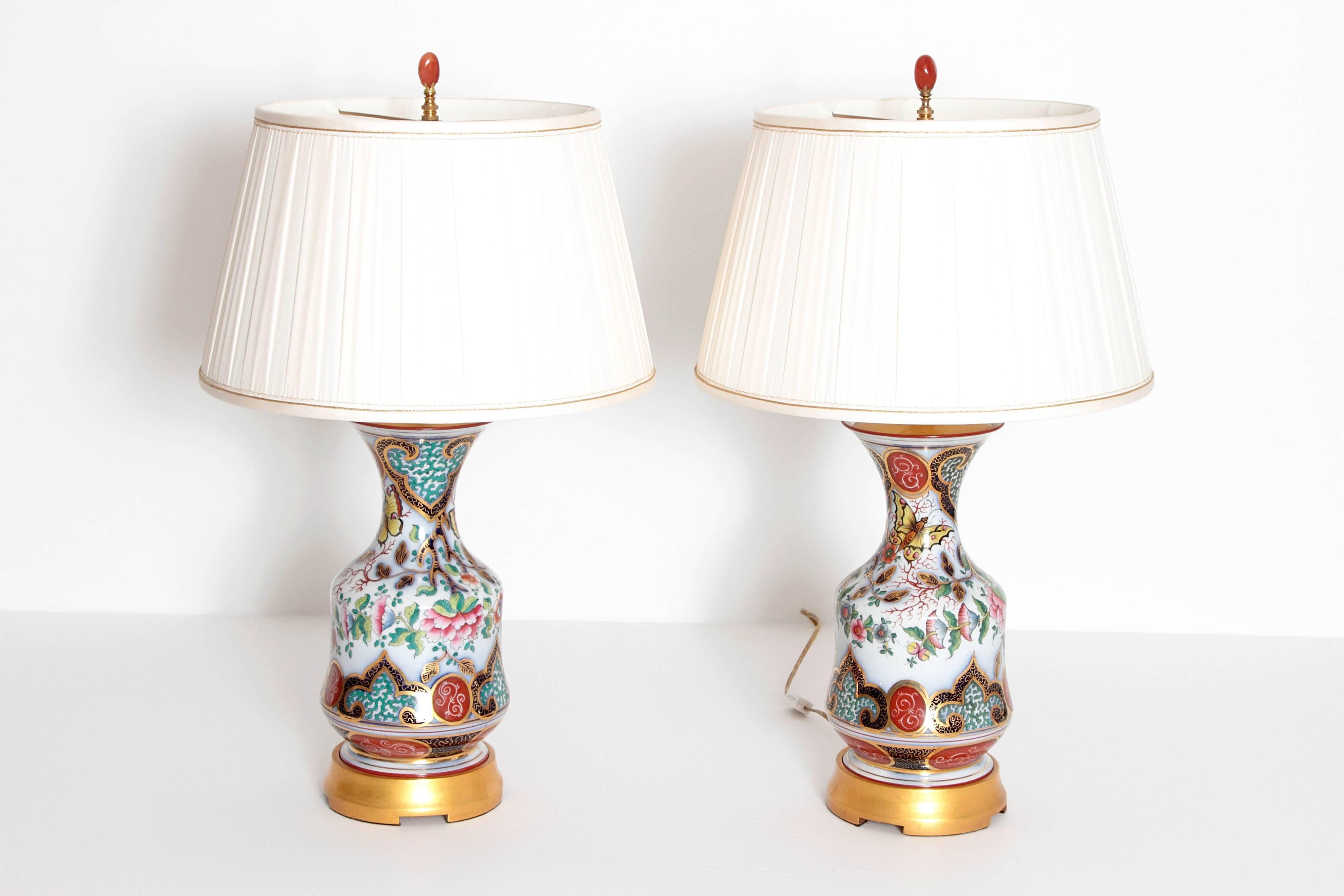 A pair of French Napoleon III hand-painted opaline glass urns converted into table lamps, on turned wood gilded bases, with custom shades.
The painted design composed of garden motifs, flower forms, butterflies and arabesque designs of varying