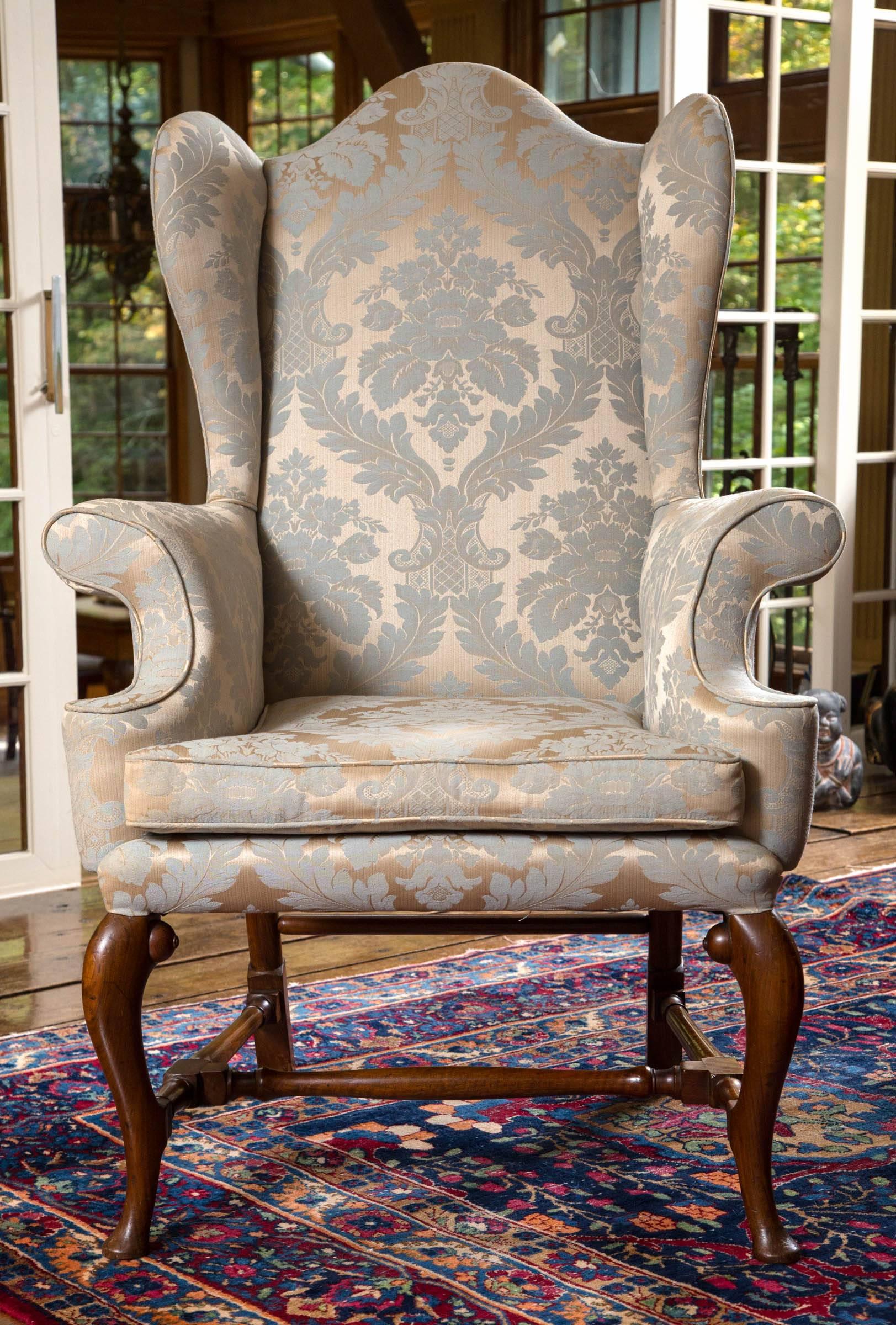 Well proportioned 19th century English wing chair in ivory and pale blue damask fabric. Legs and stretchers are mahogany. All joints are solid. Classic design with tall back and narrow wing sides.