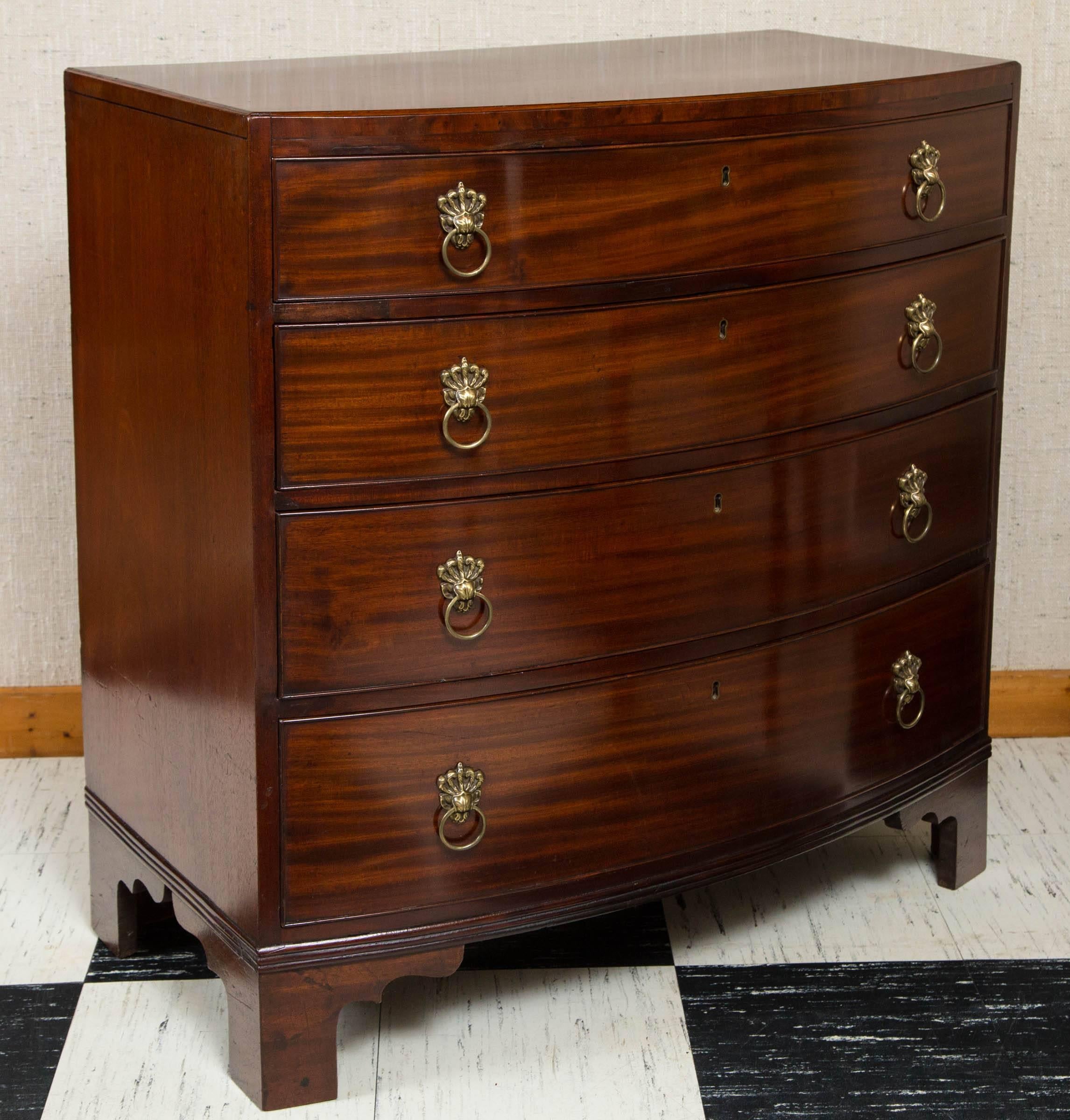 Classic bow front chest of drawers with brass ring pulls.  Four graduated drawers standing over splayed feet with reeded moulding along bottom.  Unusual ebony string inlay on the top and sides of chest.
