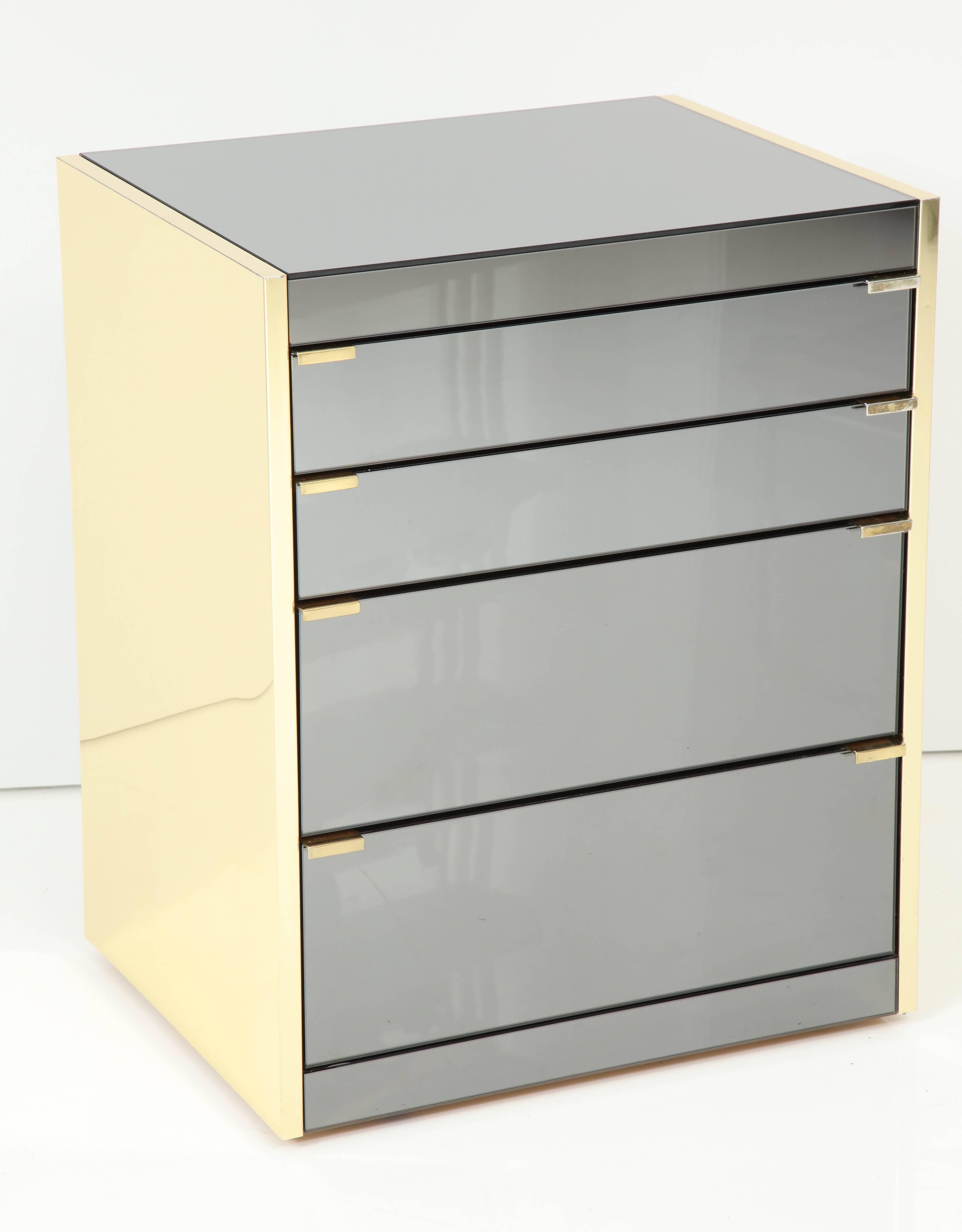 Beautiful pair of Chic cabinets by Ello Furniture company.
Both cabinets top surfaces and four drawers are in a gray mirrored glass and the sides of the cabinets are clad in polished brass.
The brass trim has a few minor scratches consistent with