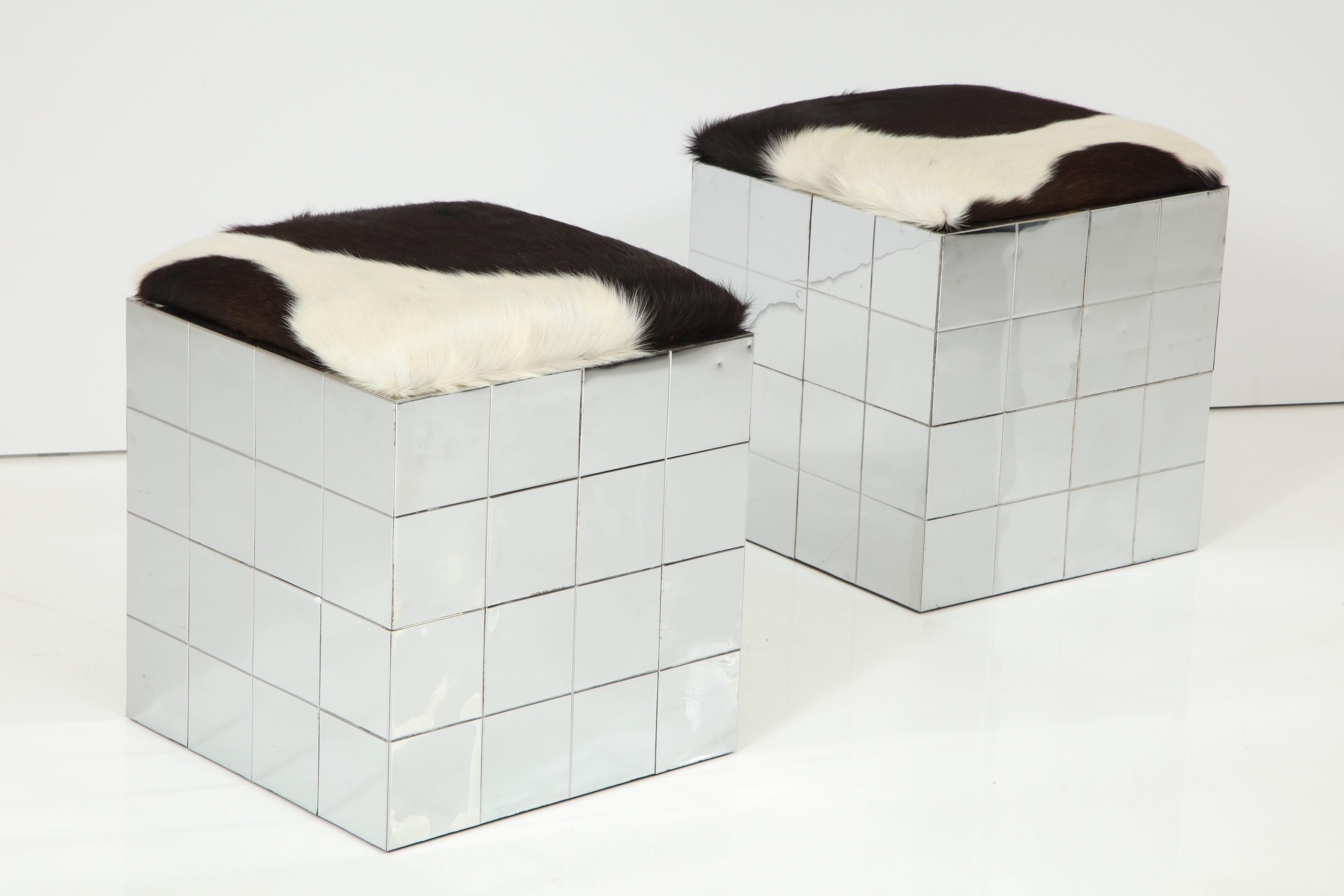 Pair of cowhide upholstered ottomans in the style of Paul Evans.
The polished chrome bases have an embossed grid pattern.
The padded tops have been newly reupholstered.
There are a few minor dings consistent with age.