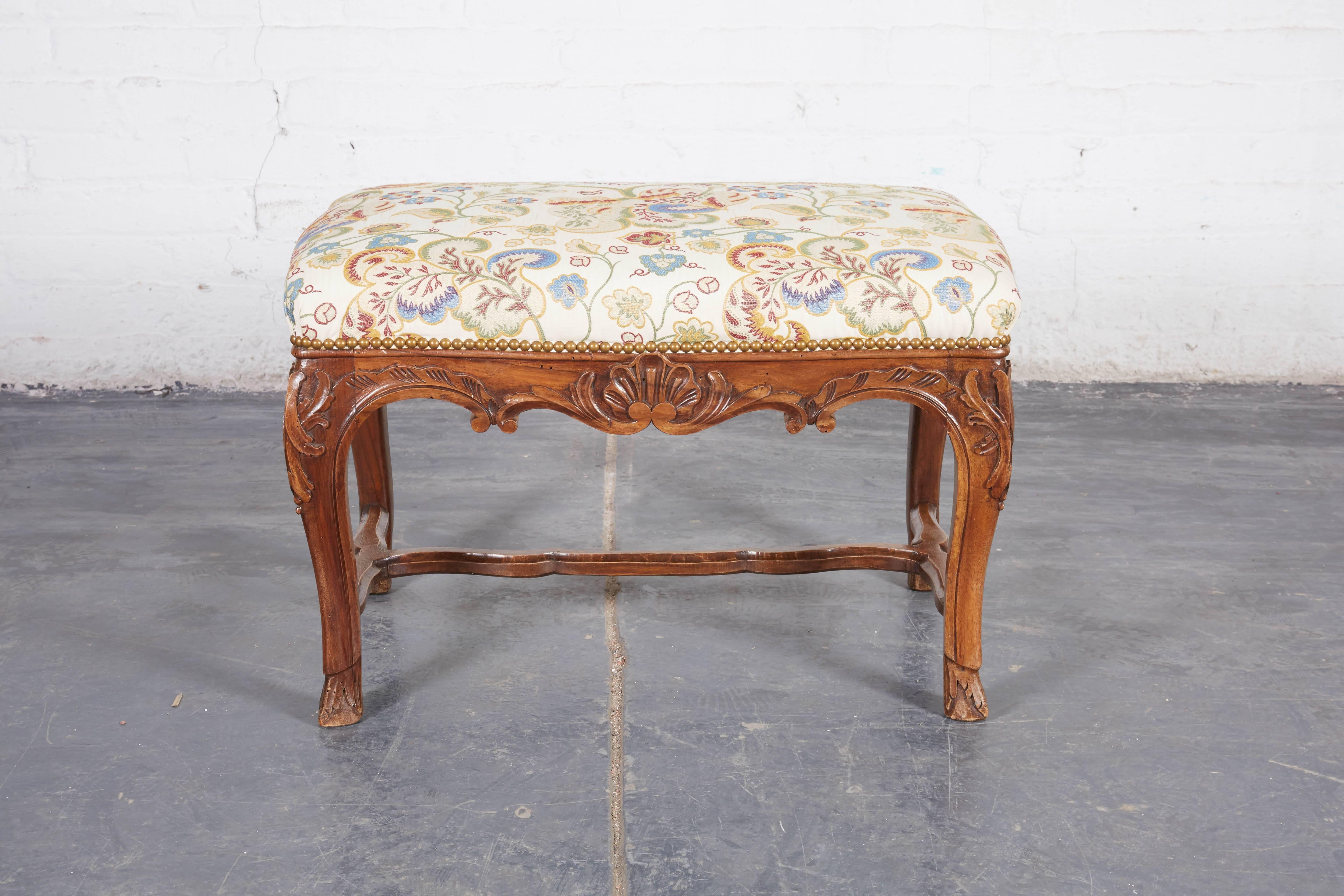 Each newly upholstered in embroidered silk with each side slightly serpentine, over the seat rail centered by shell decoration with foliate decoration to the knees; the cabriole legs joined by stretchers and terminating in pied de biche,