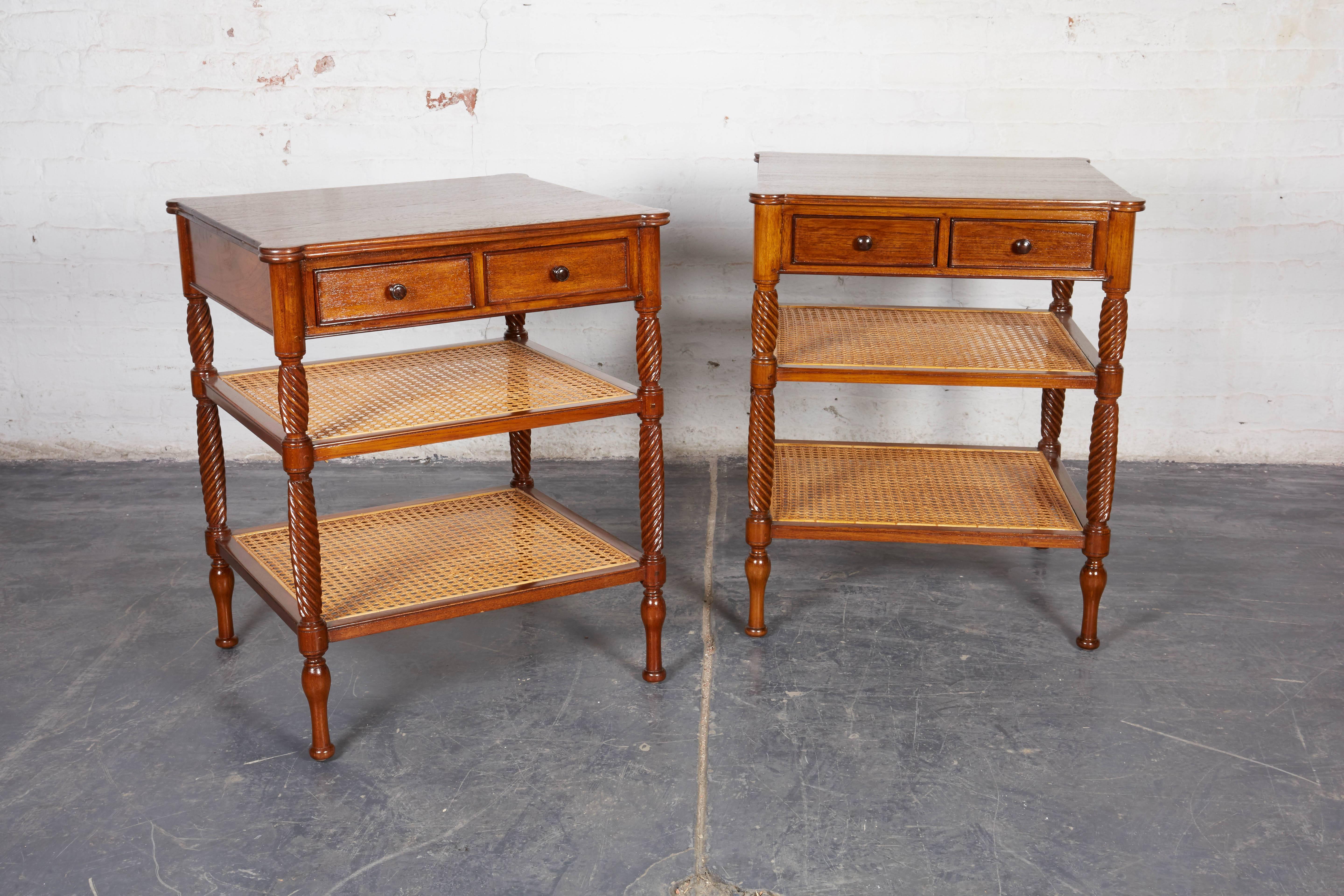 Each fitted with two short drawers over two caned shelves on bold spiral fluted supports.