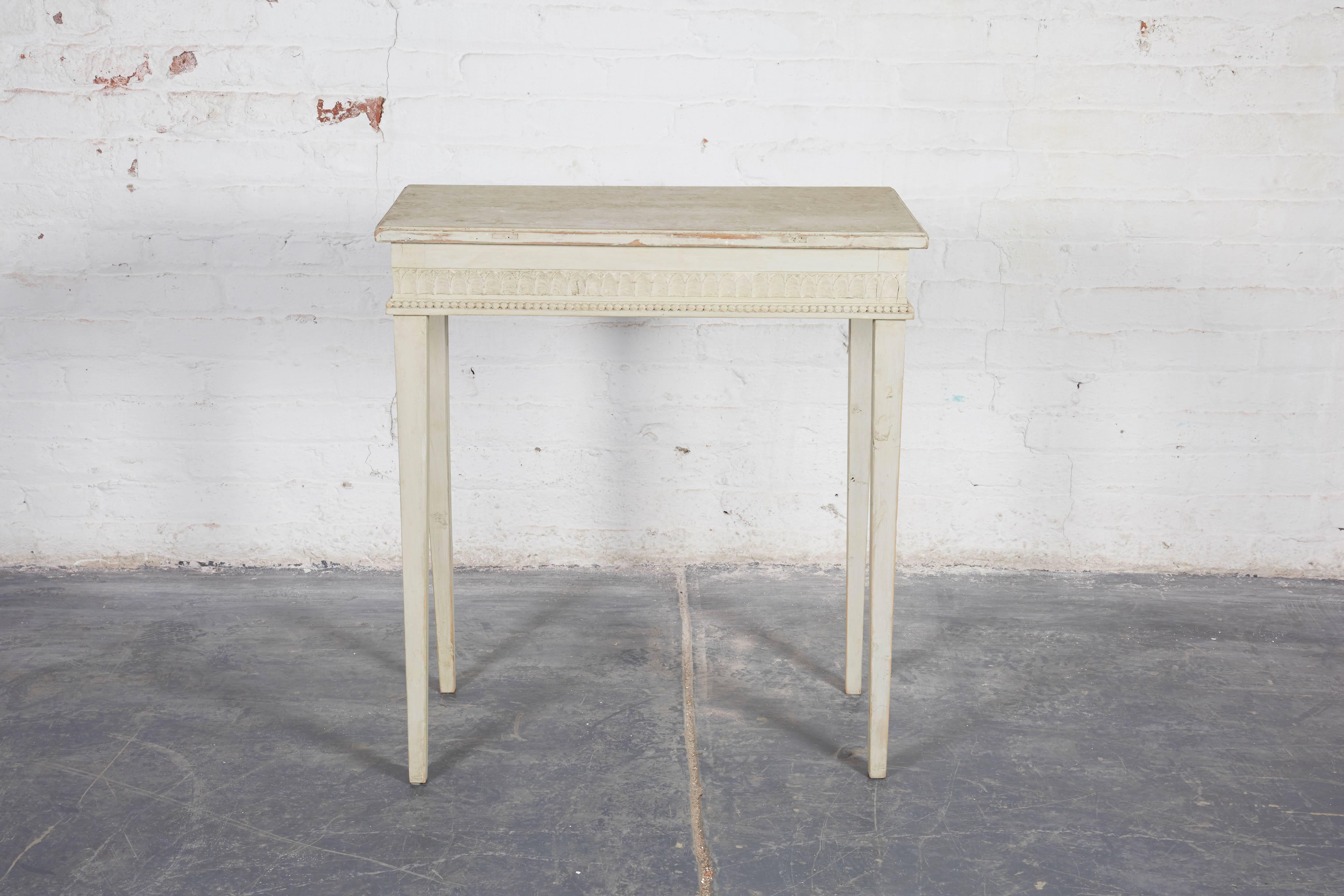 Small side table carved on all sides with white painted rectangular top (most certainly this piece had a stone top and the current top was the support), over a stiff leaf and beaded-carved frieze; raised on square tapering legs.