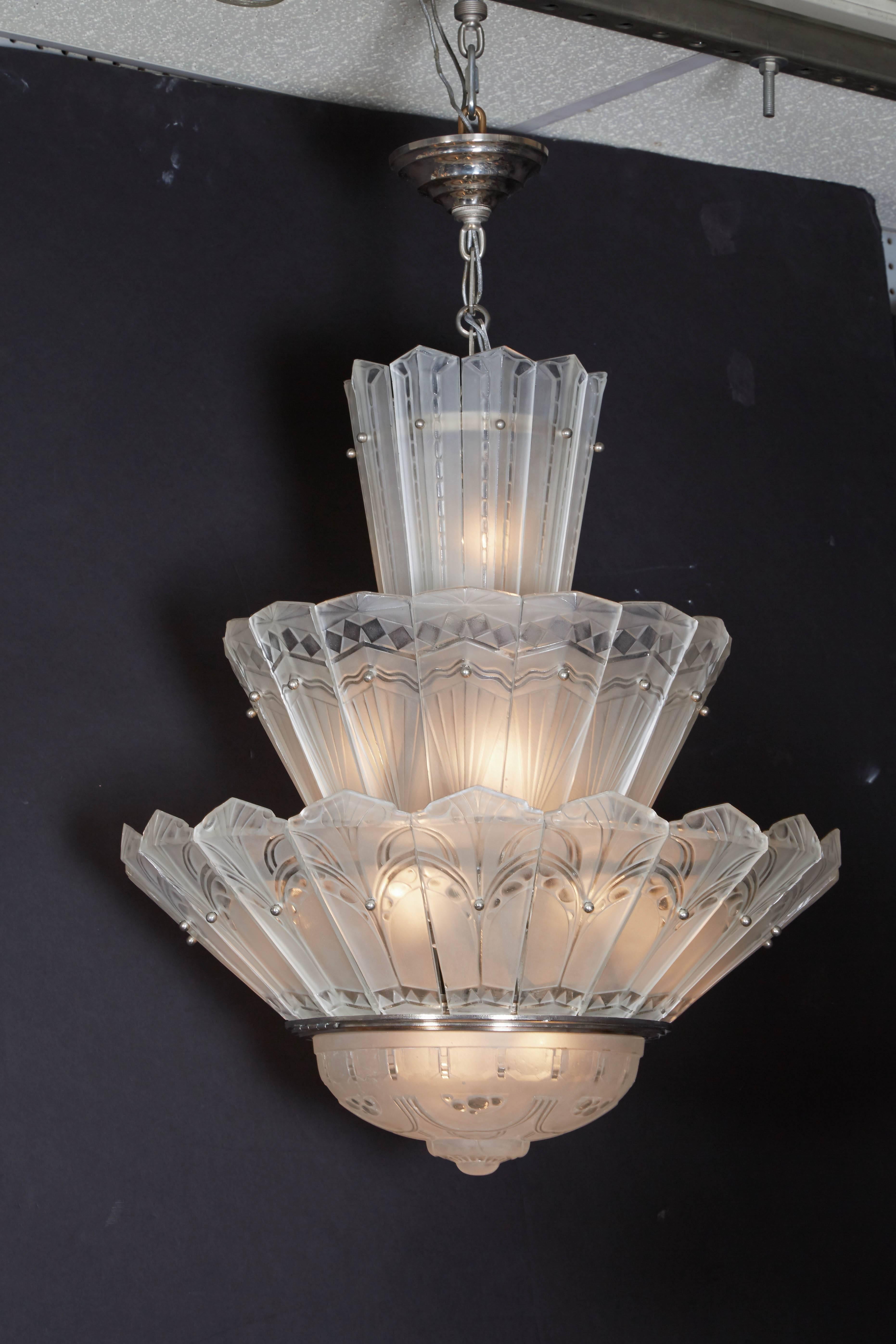 Fine and rare French Art Deco three-tier waterfall chandelier by Sabino. 
Forty-three frosted and polished molded art glass panels plus central coupe feature intentionally notable varied geometric patterns that decorate each tier. Polished nickeled