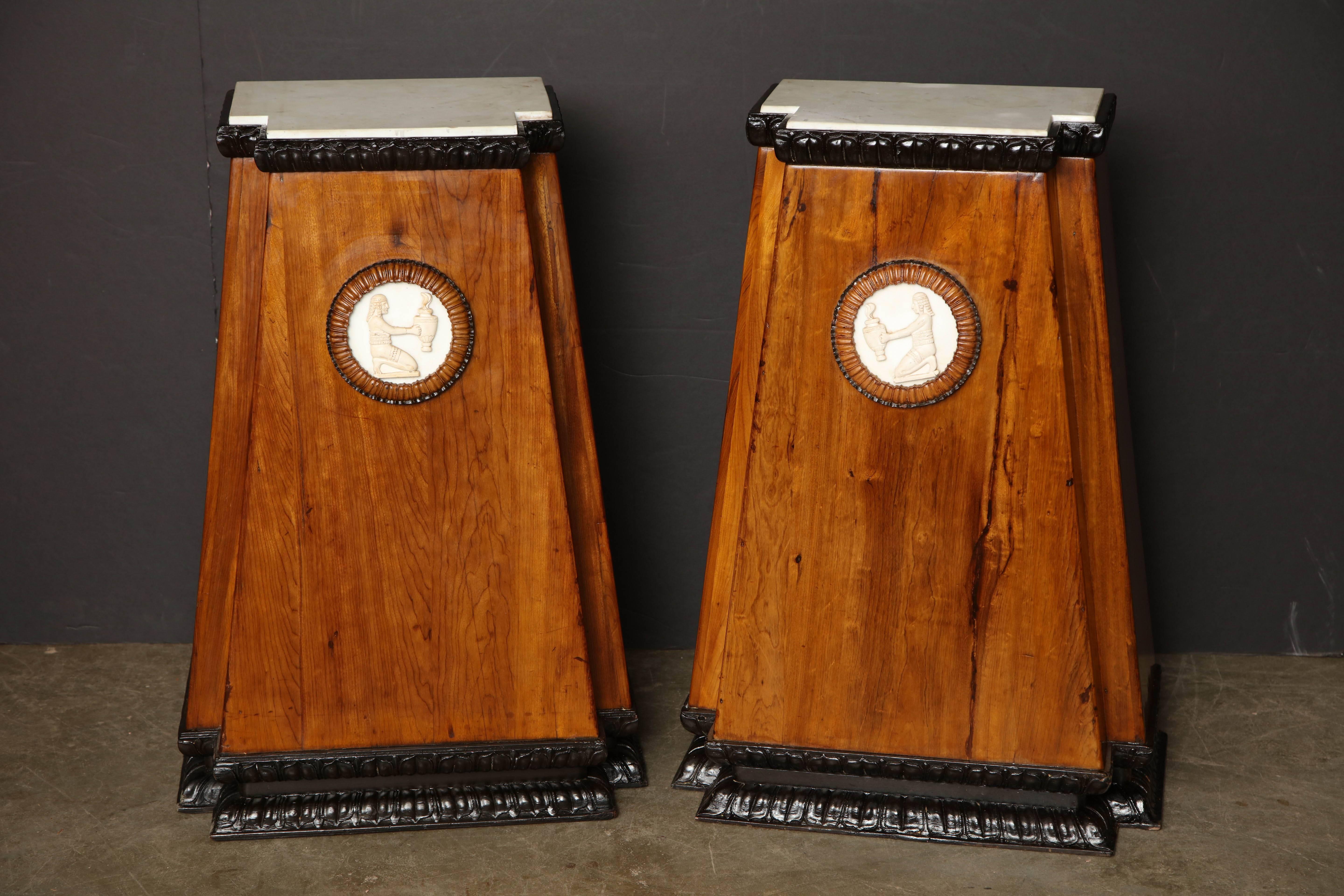 Pair of Egyptian revival Classical pyramidal form fruitwood marble top pedestals with ebonized carved moldings and applied circular marble plaques.