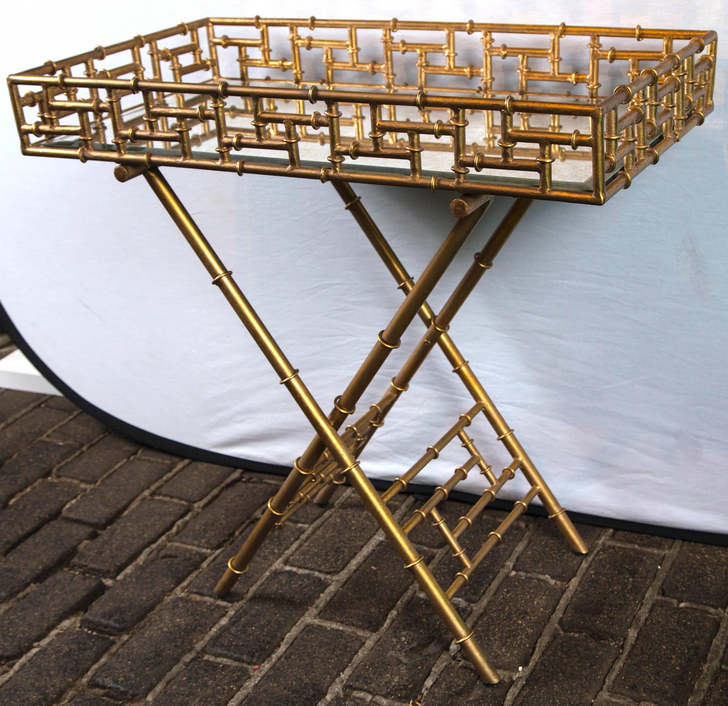 Stylish gilt chinoiserie fretwork tray table/ bar cart with antiqued mirror table surface.
 