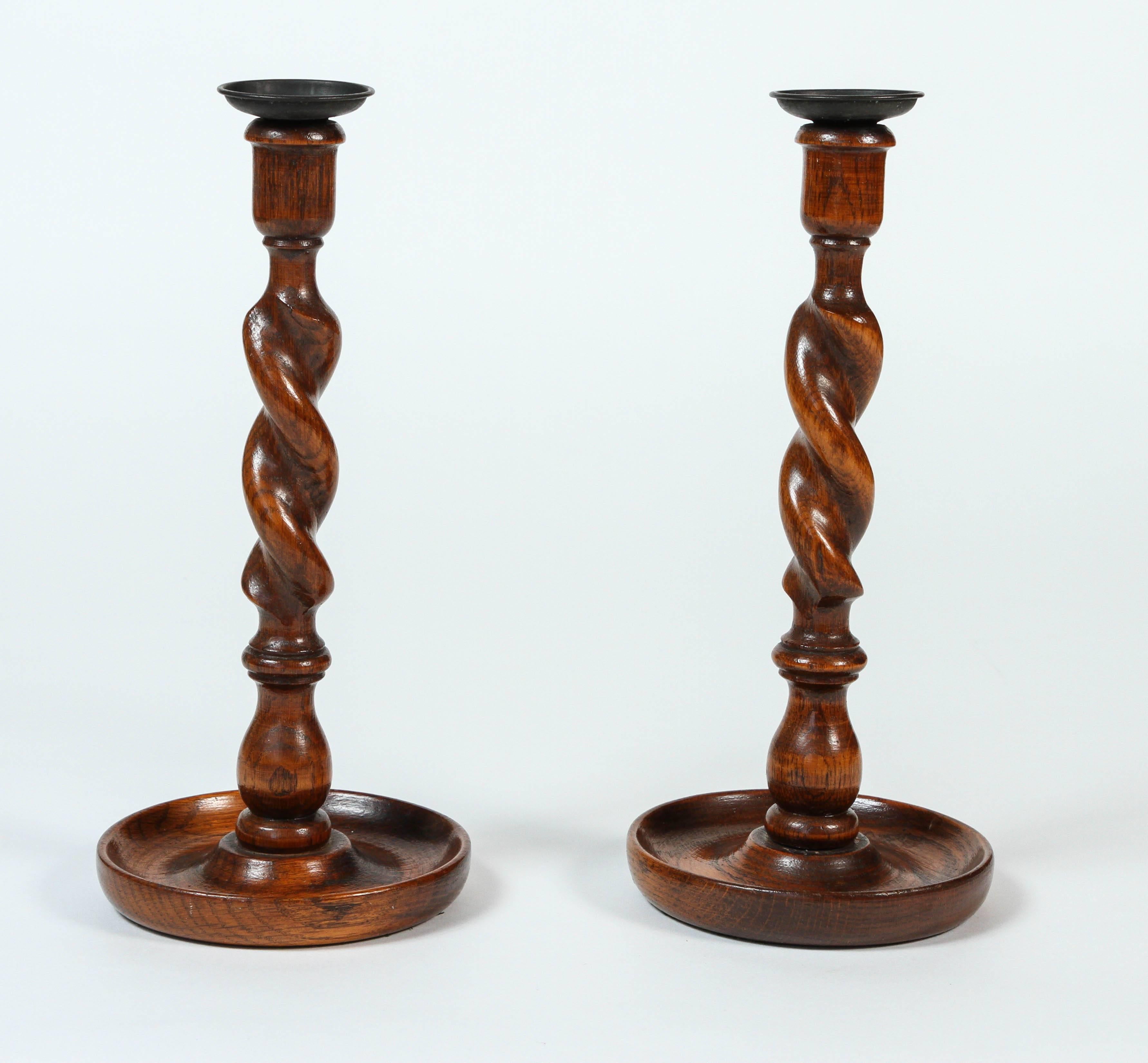 Pair of antique twisted turned wood candlesticks with black iron wax catchers and felted base.