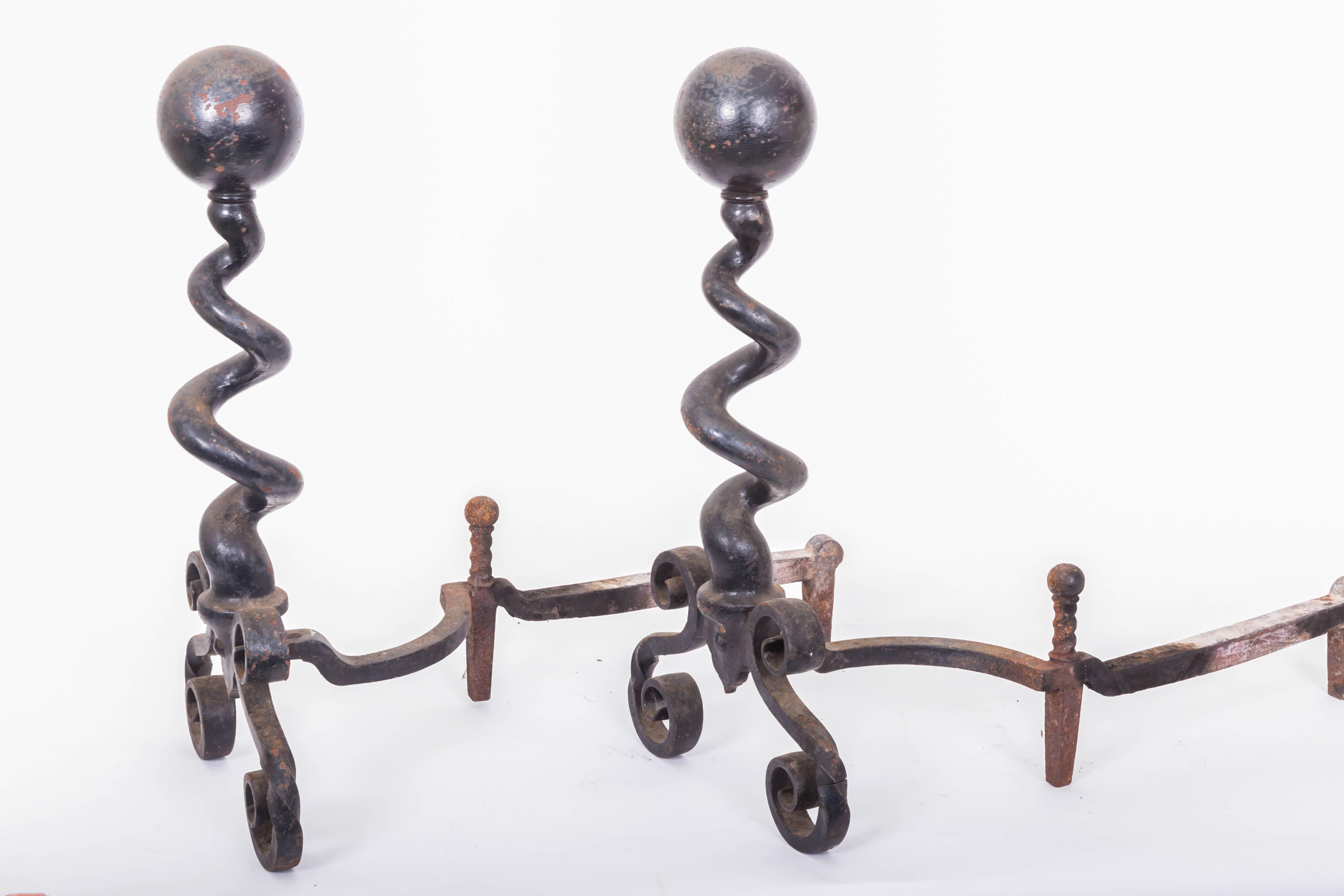 Iron, corkscrew cannonball topped andirons. Hand-forged iron andirons with cannonball finials on twisted corkscrew spiral stem and scrolled bases.