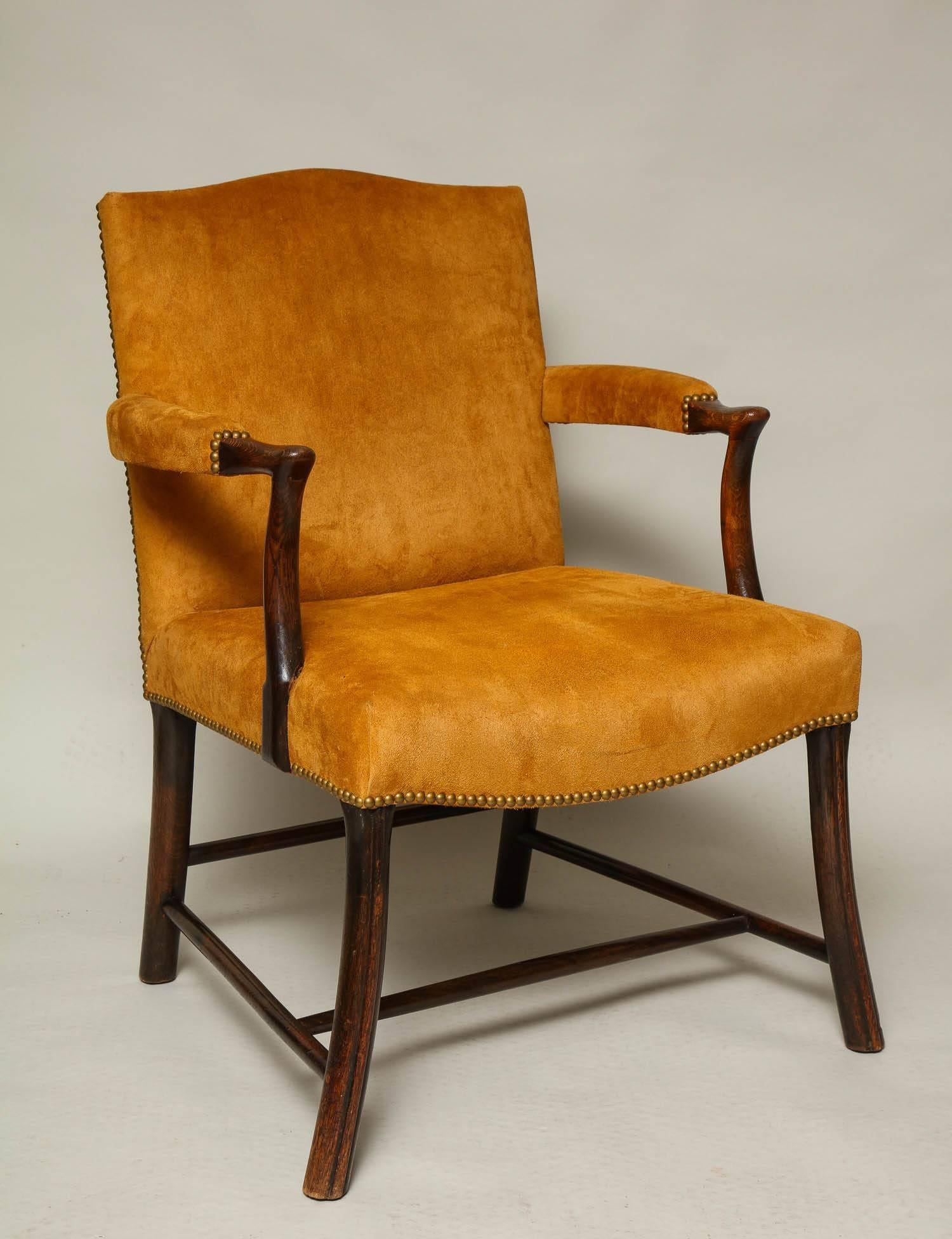 Good Scottish oak and suede Gainsborough or library chair of unusual design, the arched back over padded arms with simple rolled hands, the dished and swell fronted seat with close nail decoration and standing on unusual channeled outswept legs